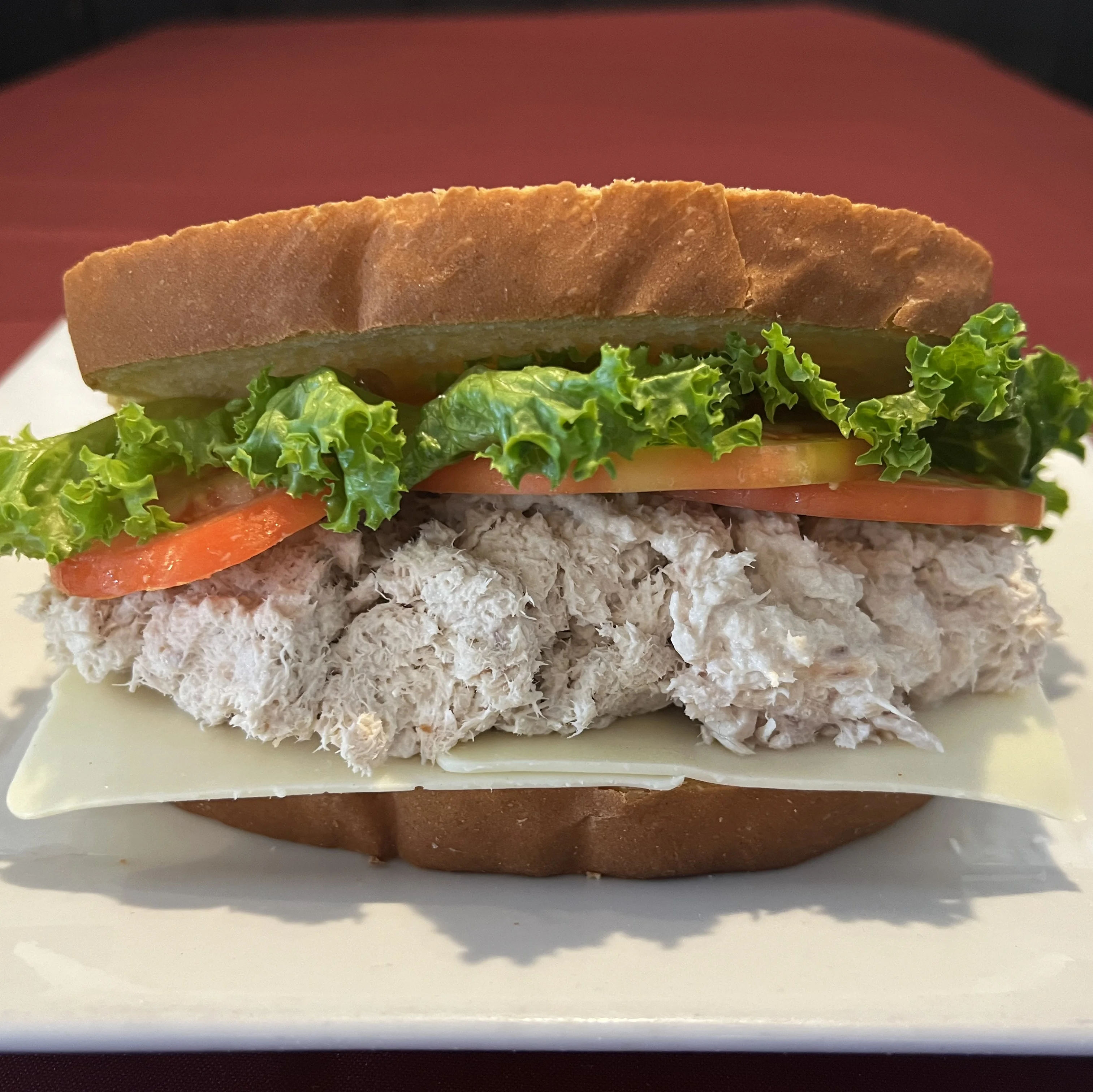 Tuna cheese sandwich on a plate with fresh ingredients