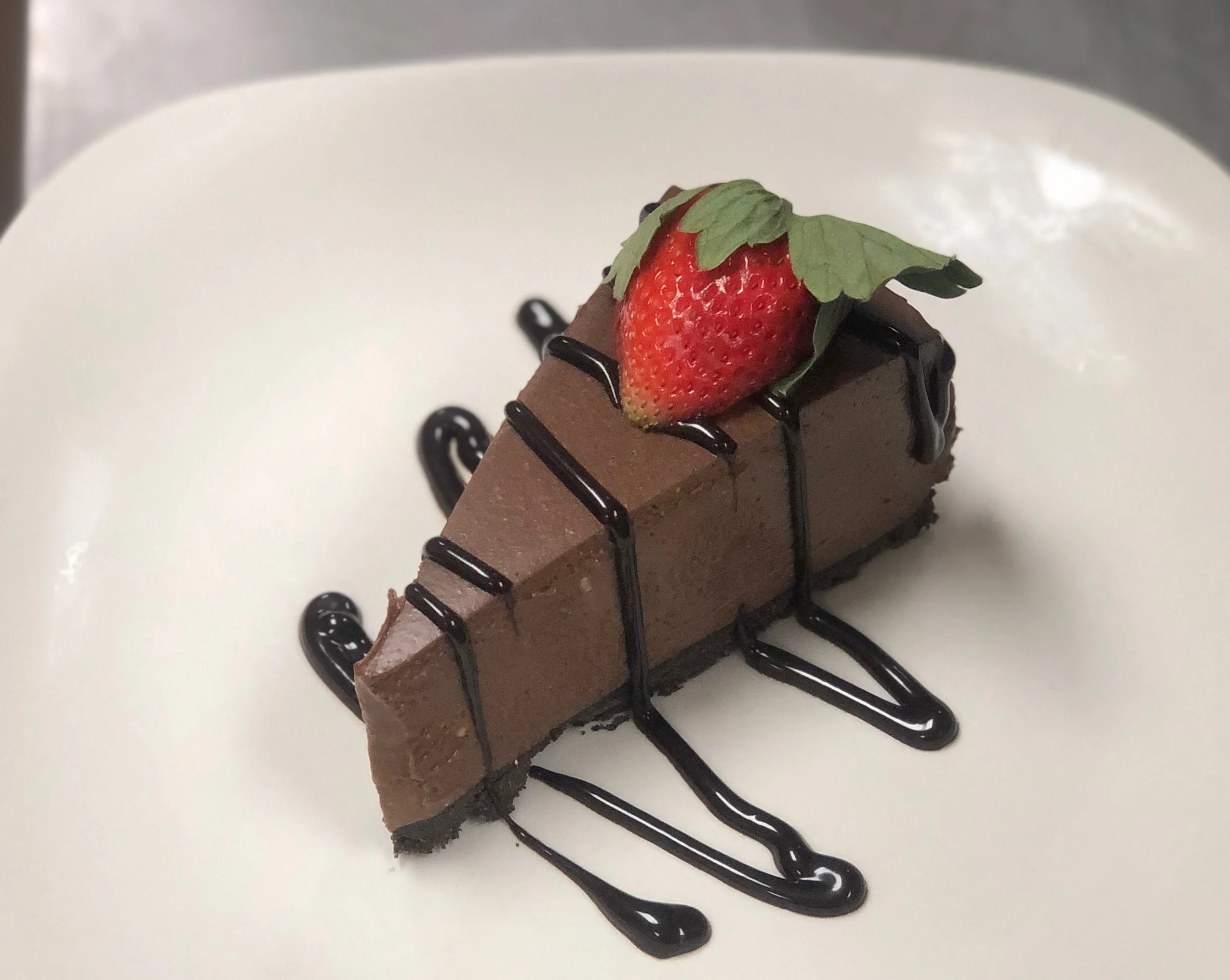 Decadent chocolate cheesecake slice with strawberry garnish