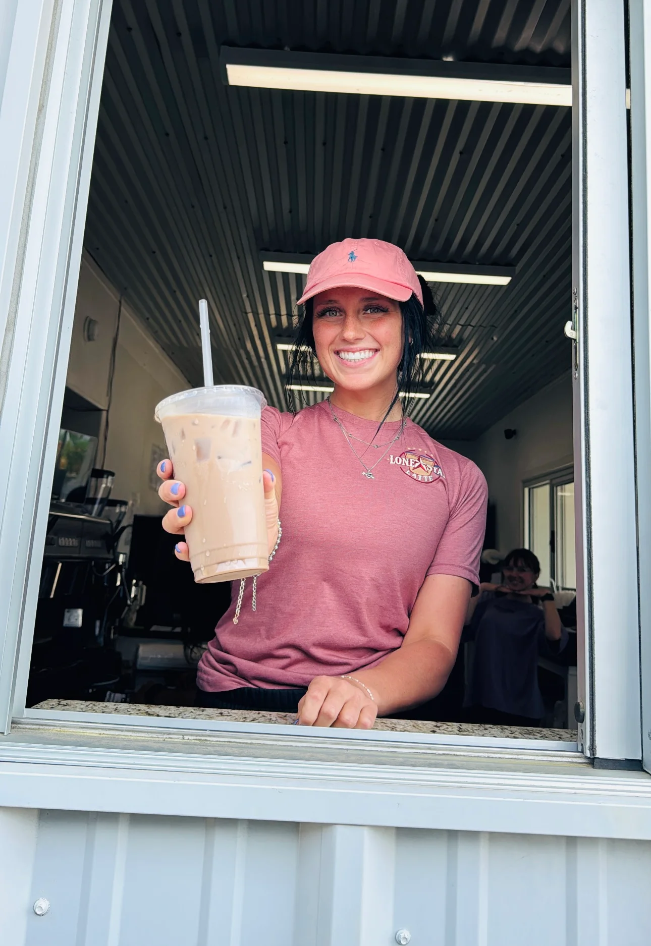 Barista serving iced coffee at a drive-thru window
