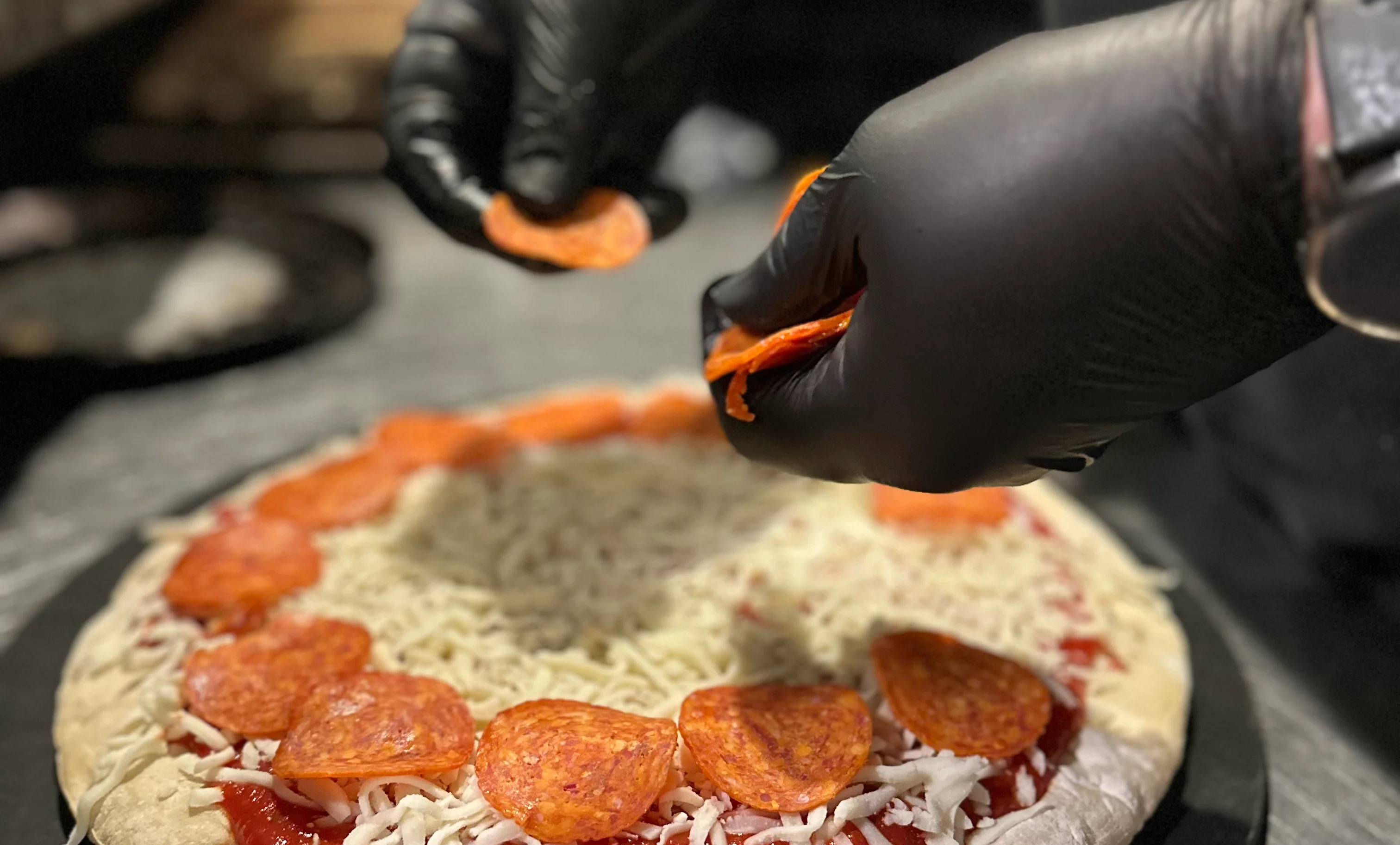 Hands shaping pizza dough on a wooden surface.