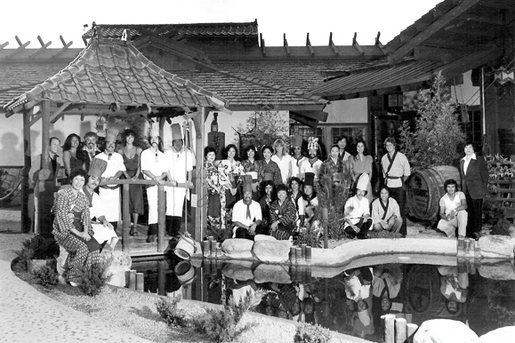 Group of restaurant staff in traditional attire by a pond