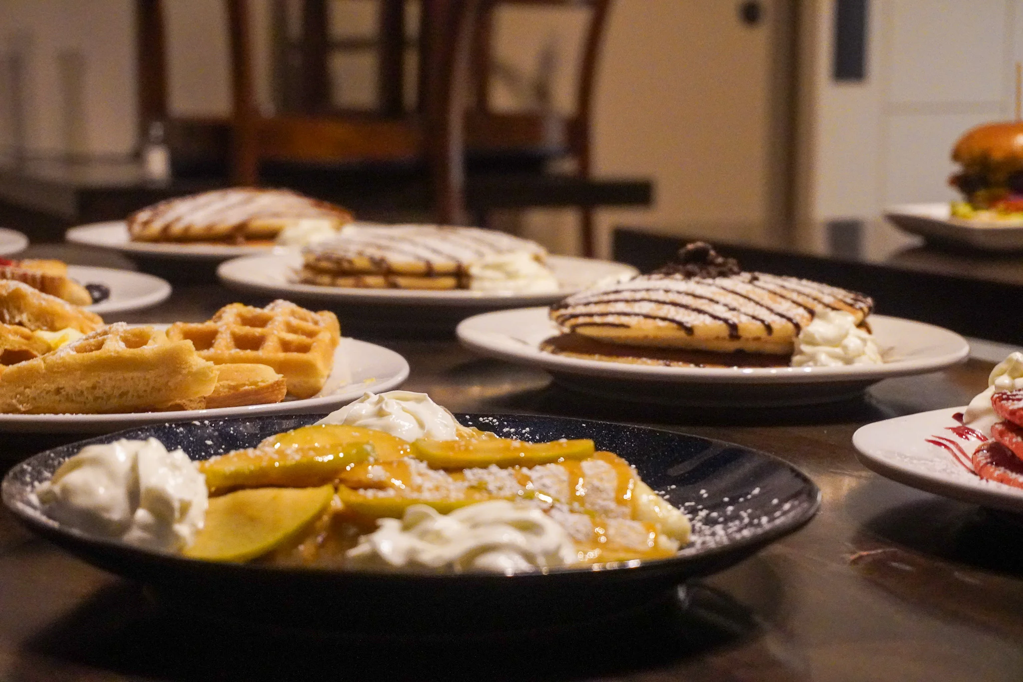 Delicious stack of pancakes with whipped cream and waffles in a cozy restaurant setting