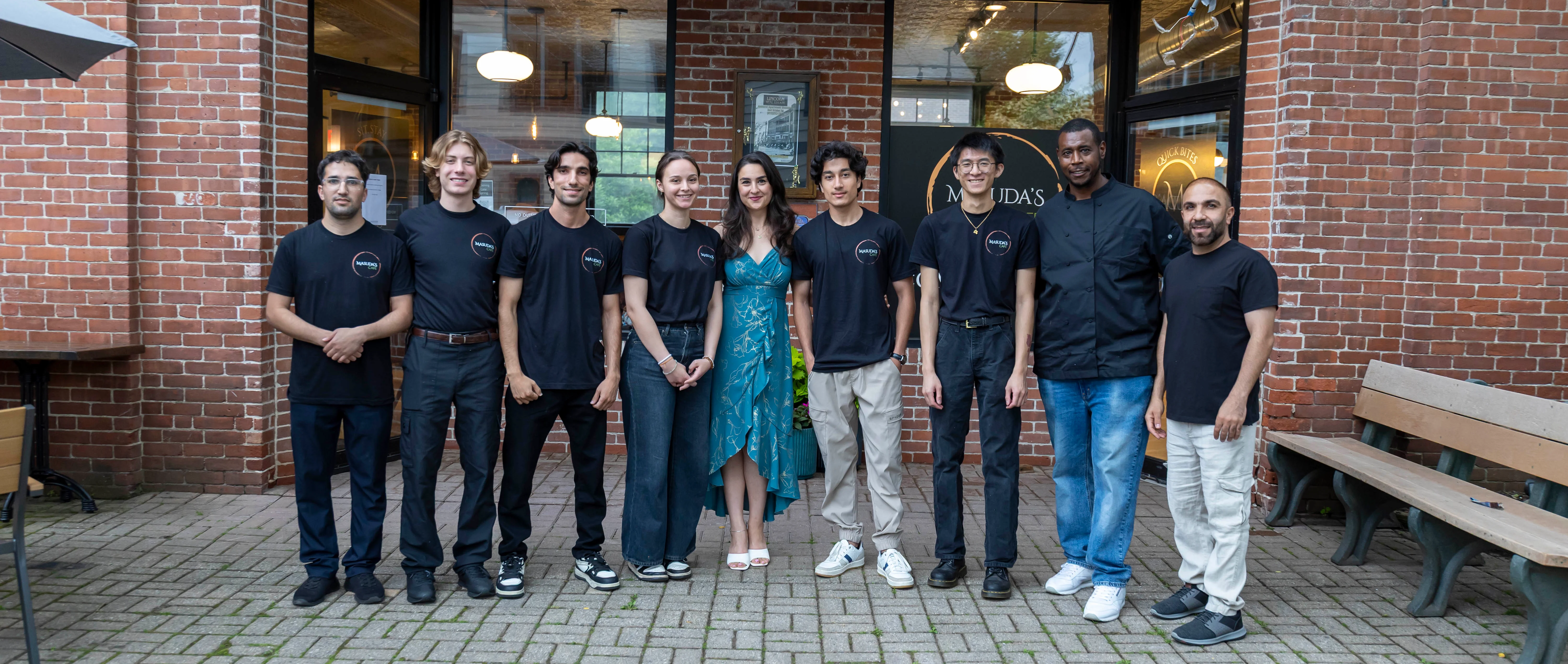 Restaurant staff posing outside a cozy eatery with brick facade