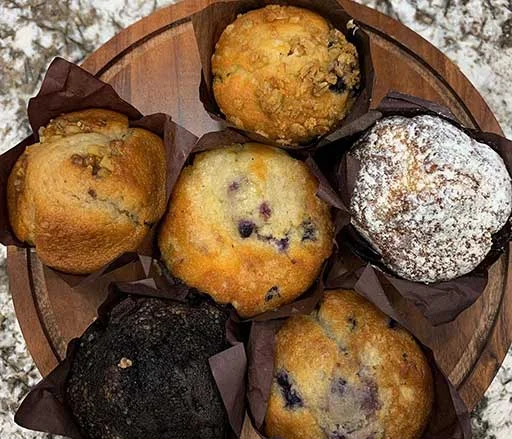 Assorted gourmet muffins on a wooden platter
