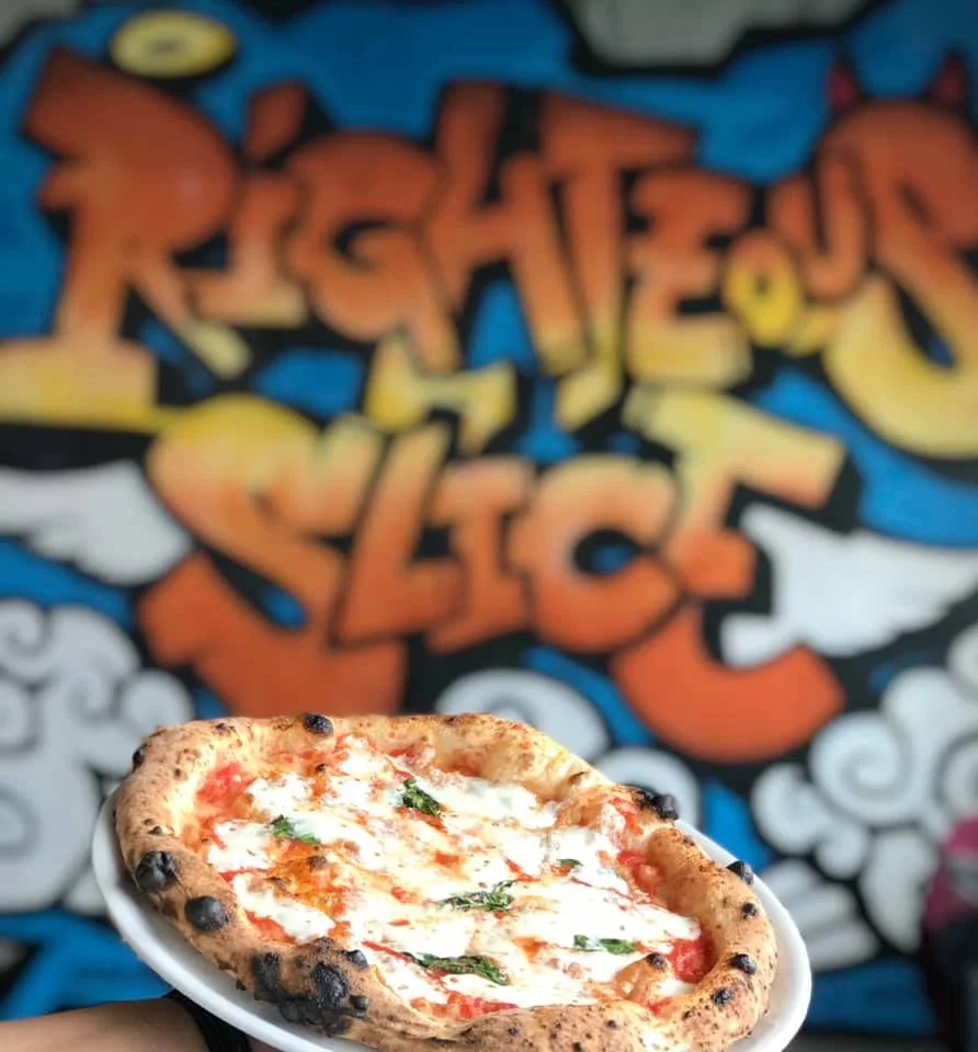 Margherita pizza served on a plate with vibrant graffiti backdrop