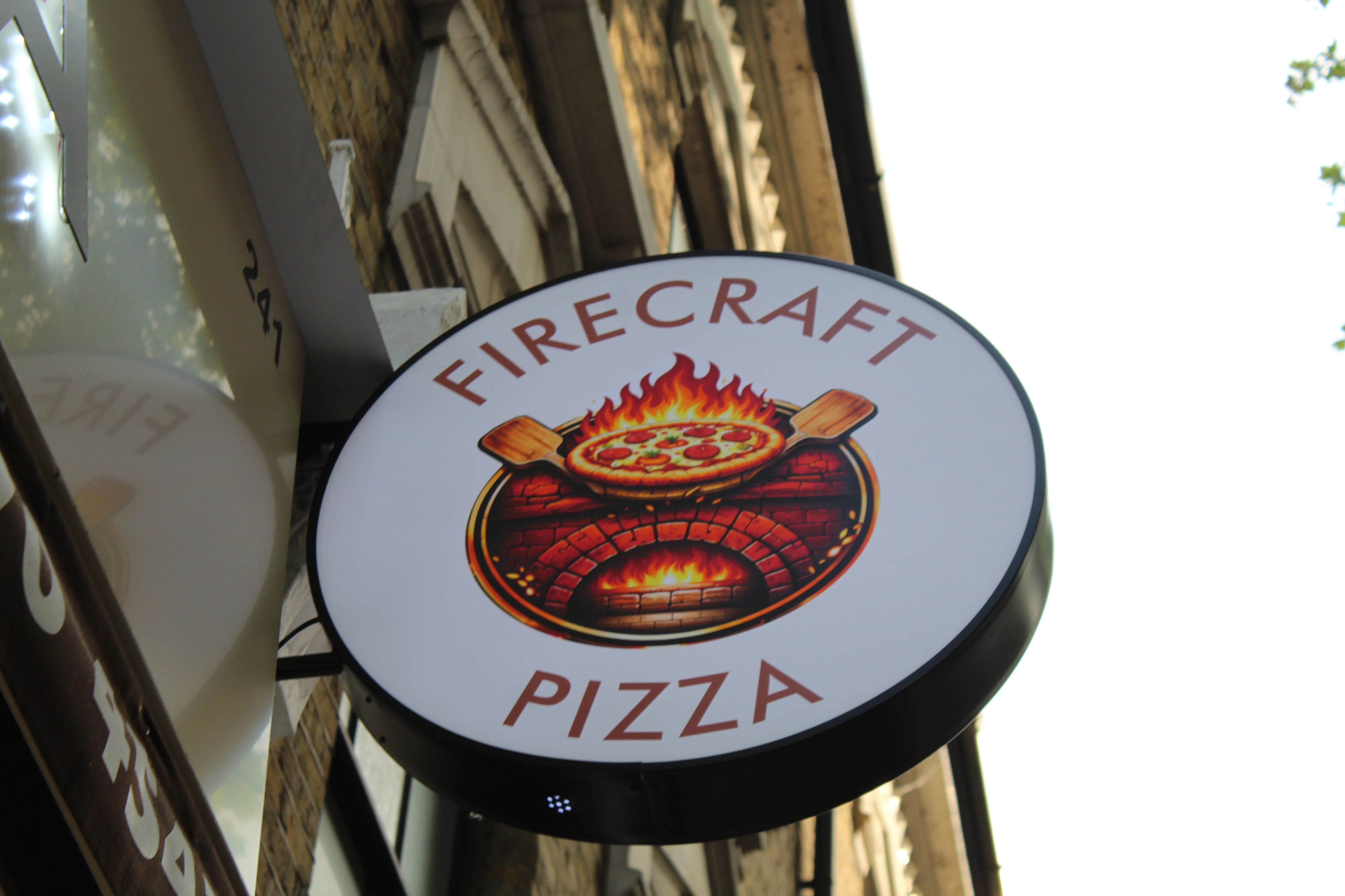 Firecraft Pizza restaurant sign featuring a wood-fired pizza design