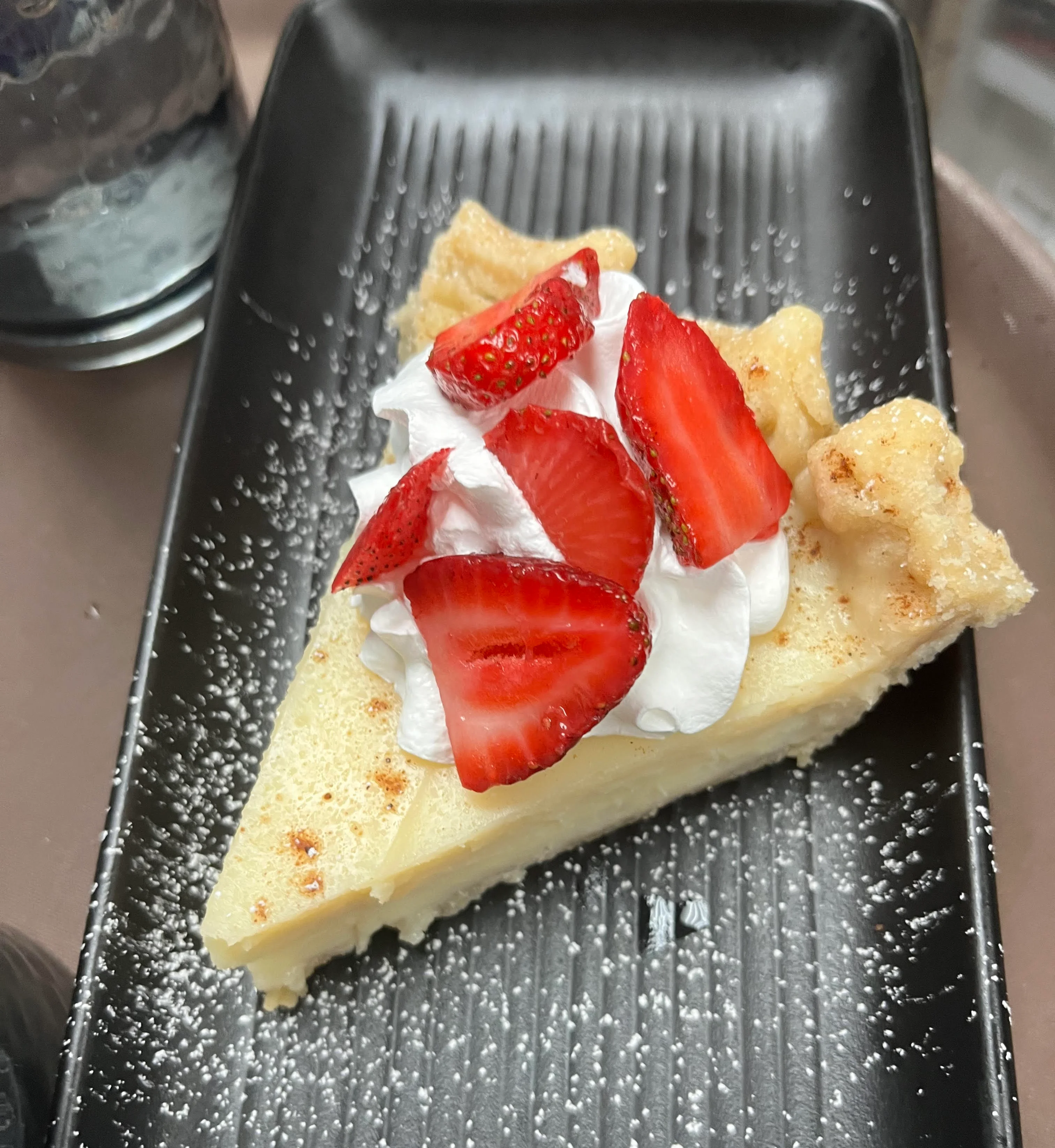 Slice of classic cheesecake topped with fresh strawberries and whipped cream