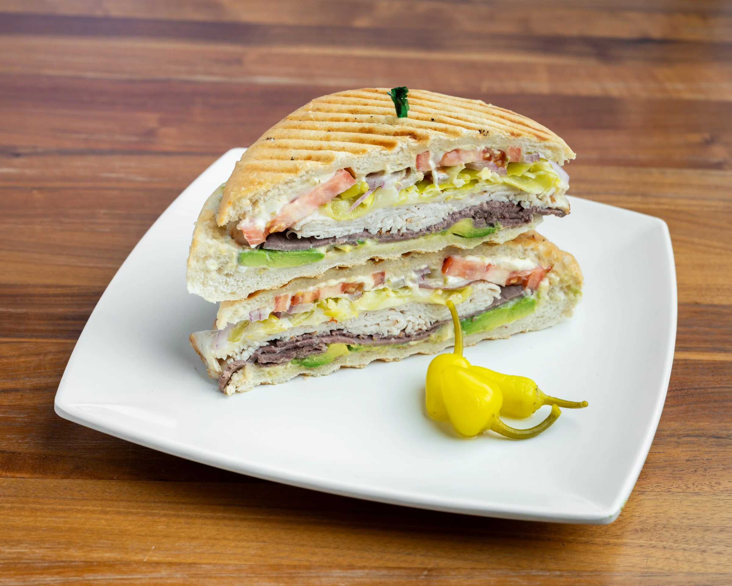 Cuban sandwich with layers of meat and vegetables on a white plate