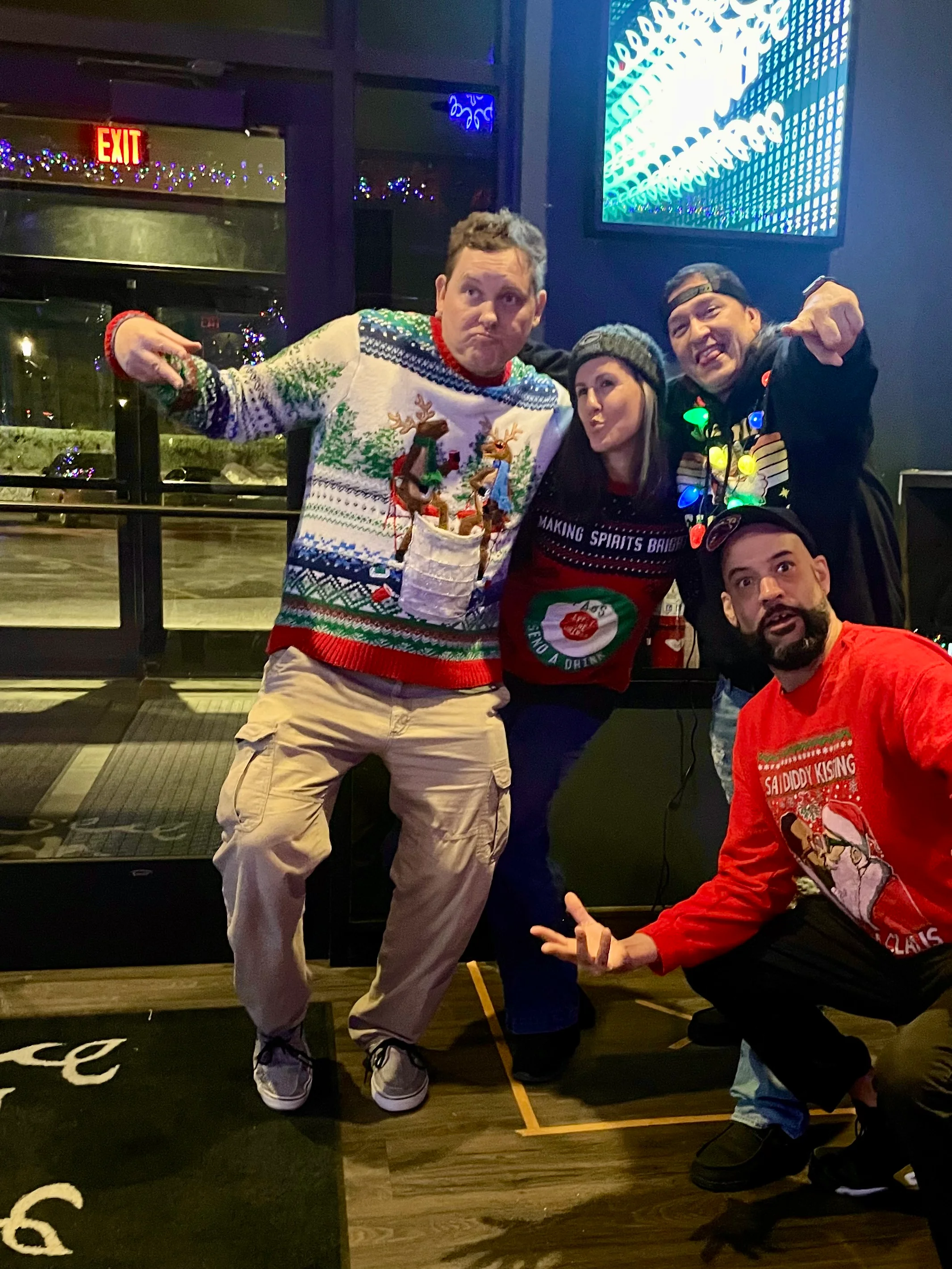 Group of friends in festive sweaters posing at a holiday party