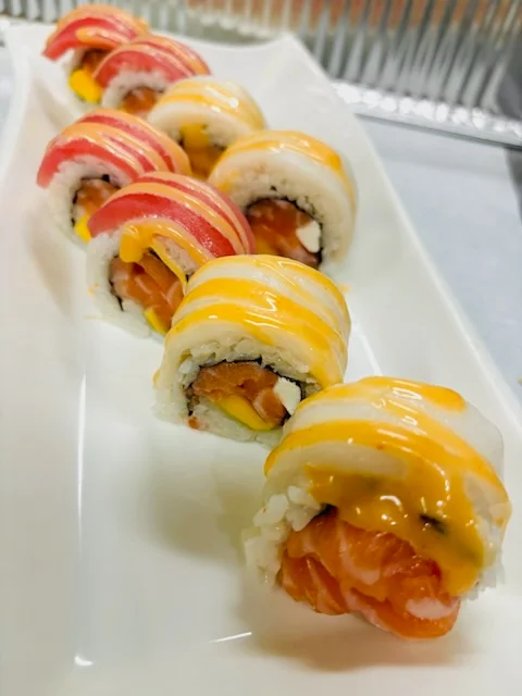 Colorful sushi rolls with creamy sauce on a white plate