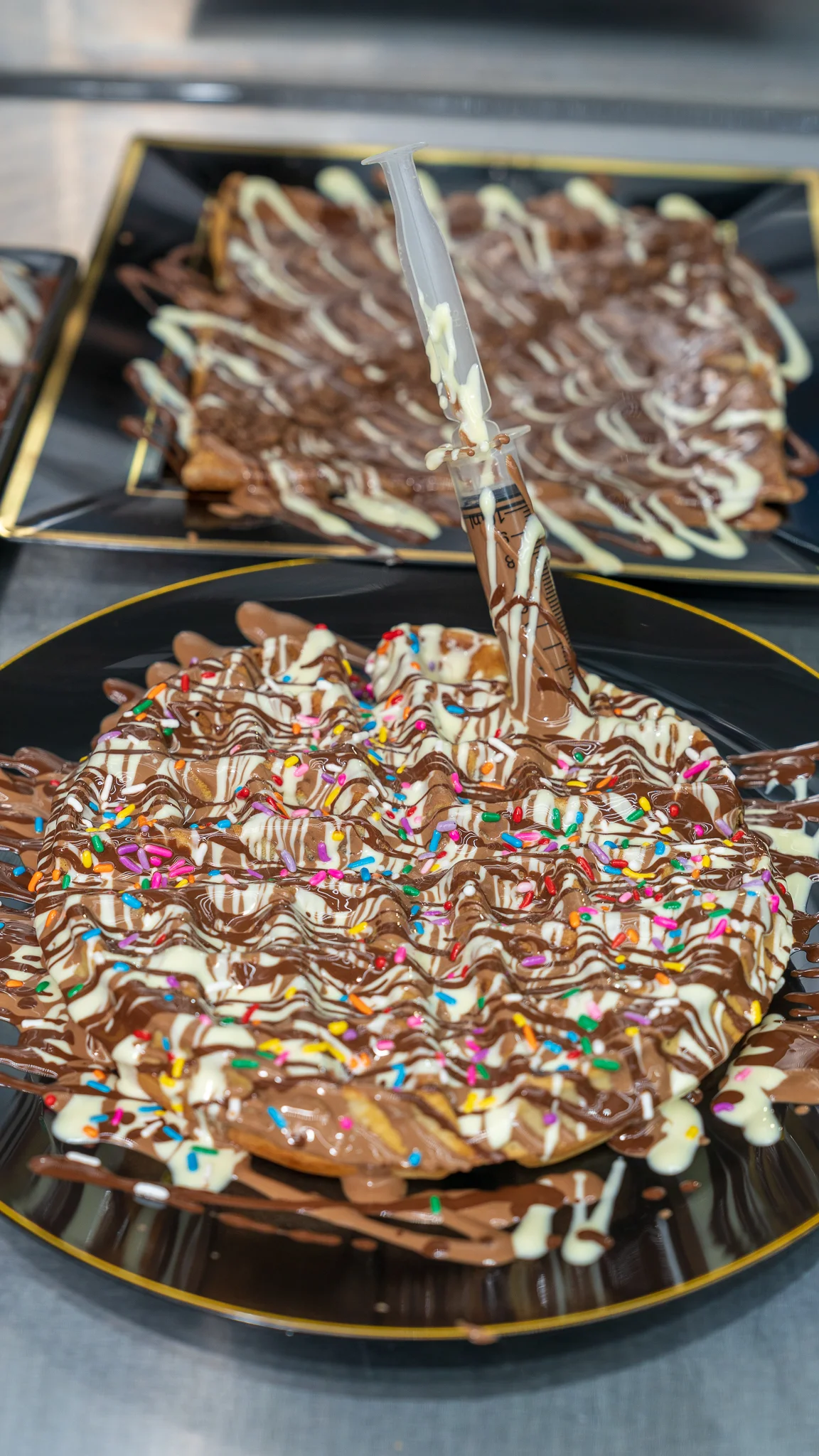 Decadent chocolate waffle with sprinkles and sauce injector