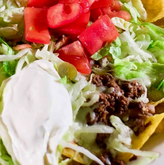 Delicious plate of Mexican nachos topped with fresh vegetables