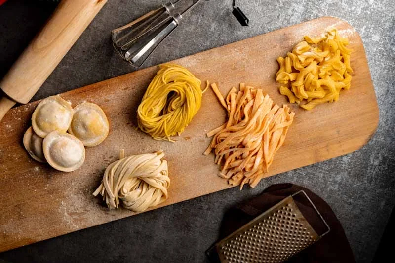 Variety of fresh Italian pasta on a wooden board