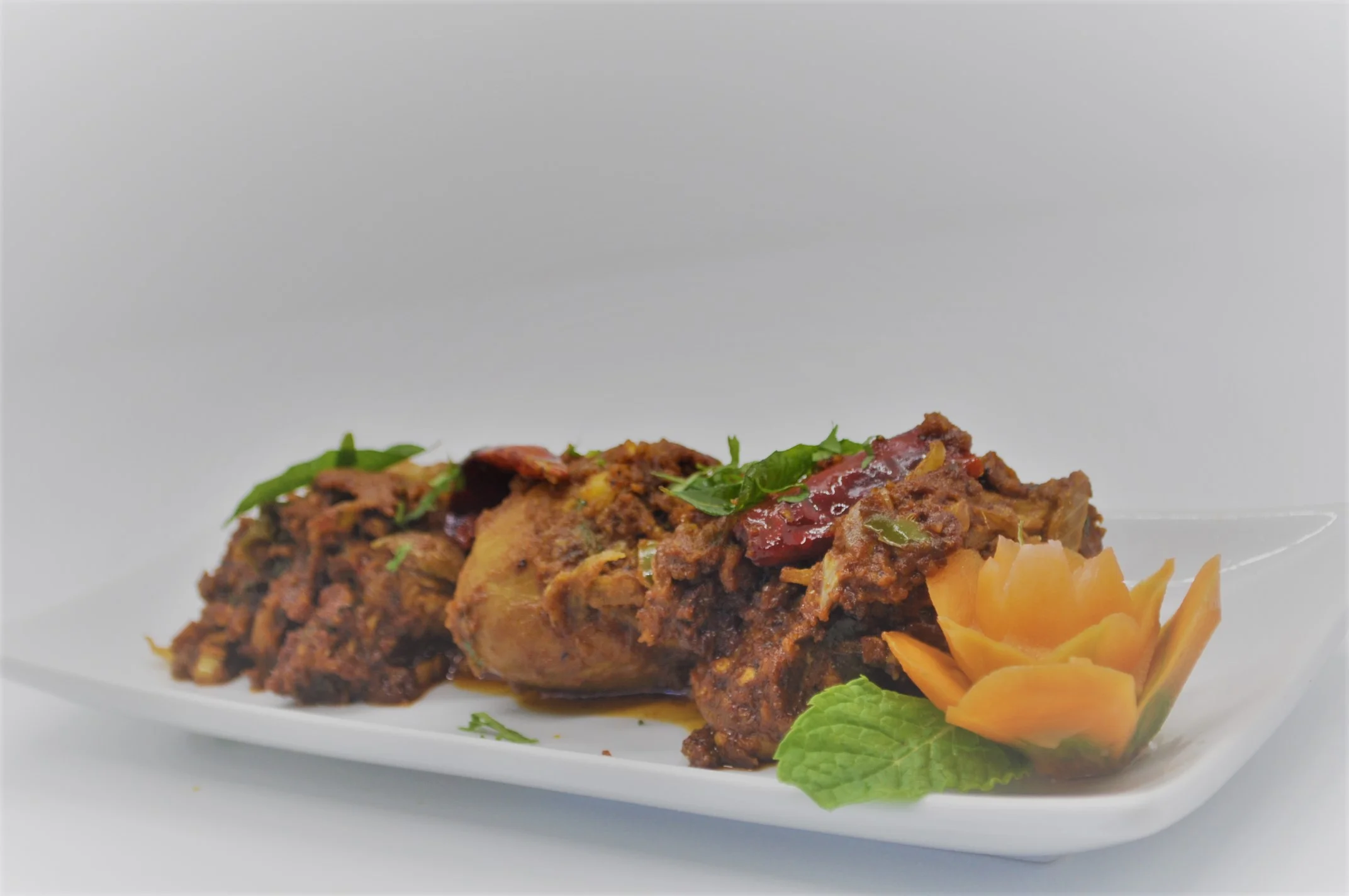 Spicy Indian chicken curry with herbs and garnishes