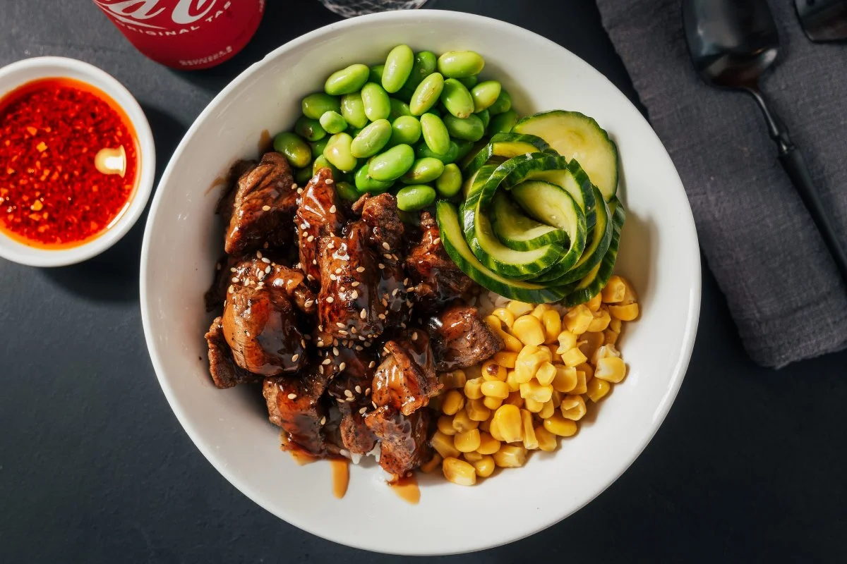 A delicious steak donburi served in a bowl with rice and garnishes.