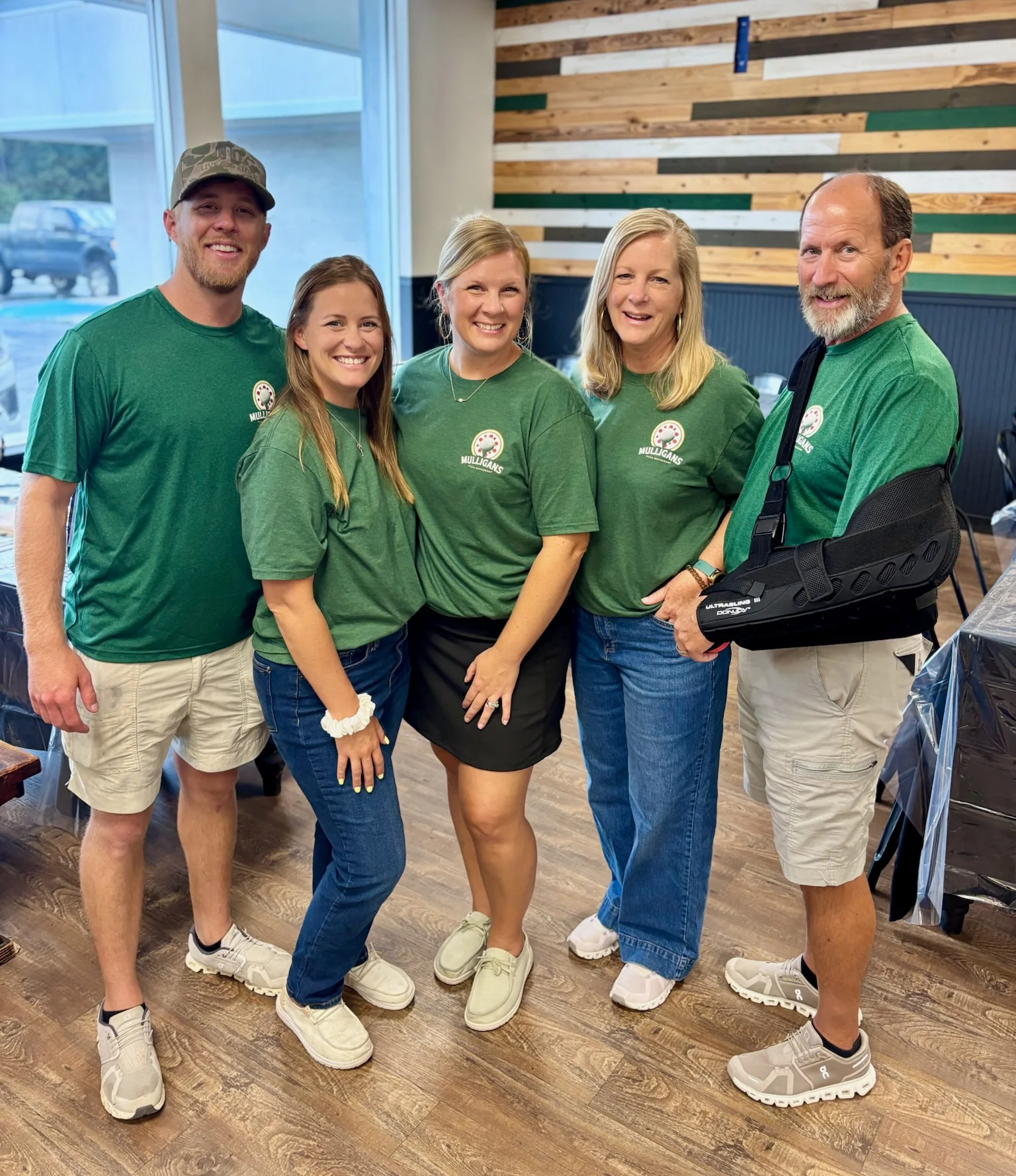 Team of restaurant staff posing together in green shirts