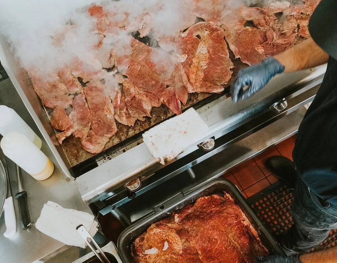 Sizzling carne asada on a grill in a busy kitchen