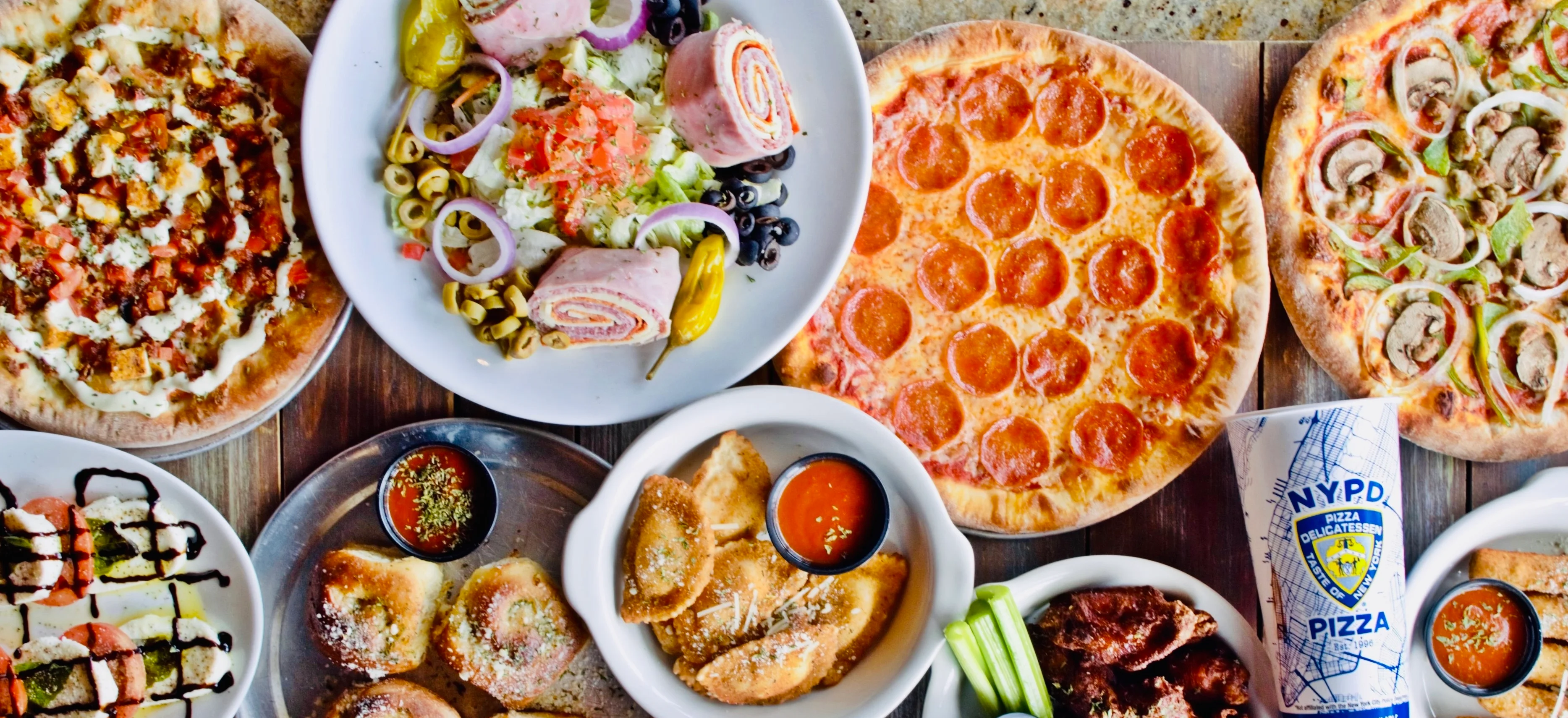 Variety of Italian pizzas and appetizers on a rustic table