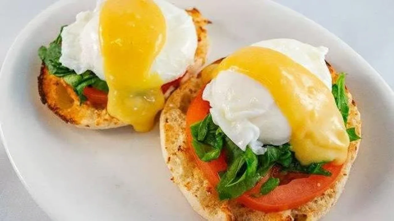 Moonlite Diner Eggs Benedict with poached eggs, fresh tomatoes, greens, and creamy hollandaise sauce on toasted English muffins.