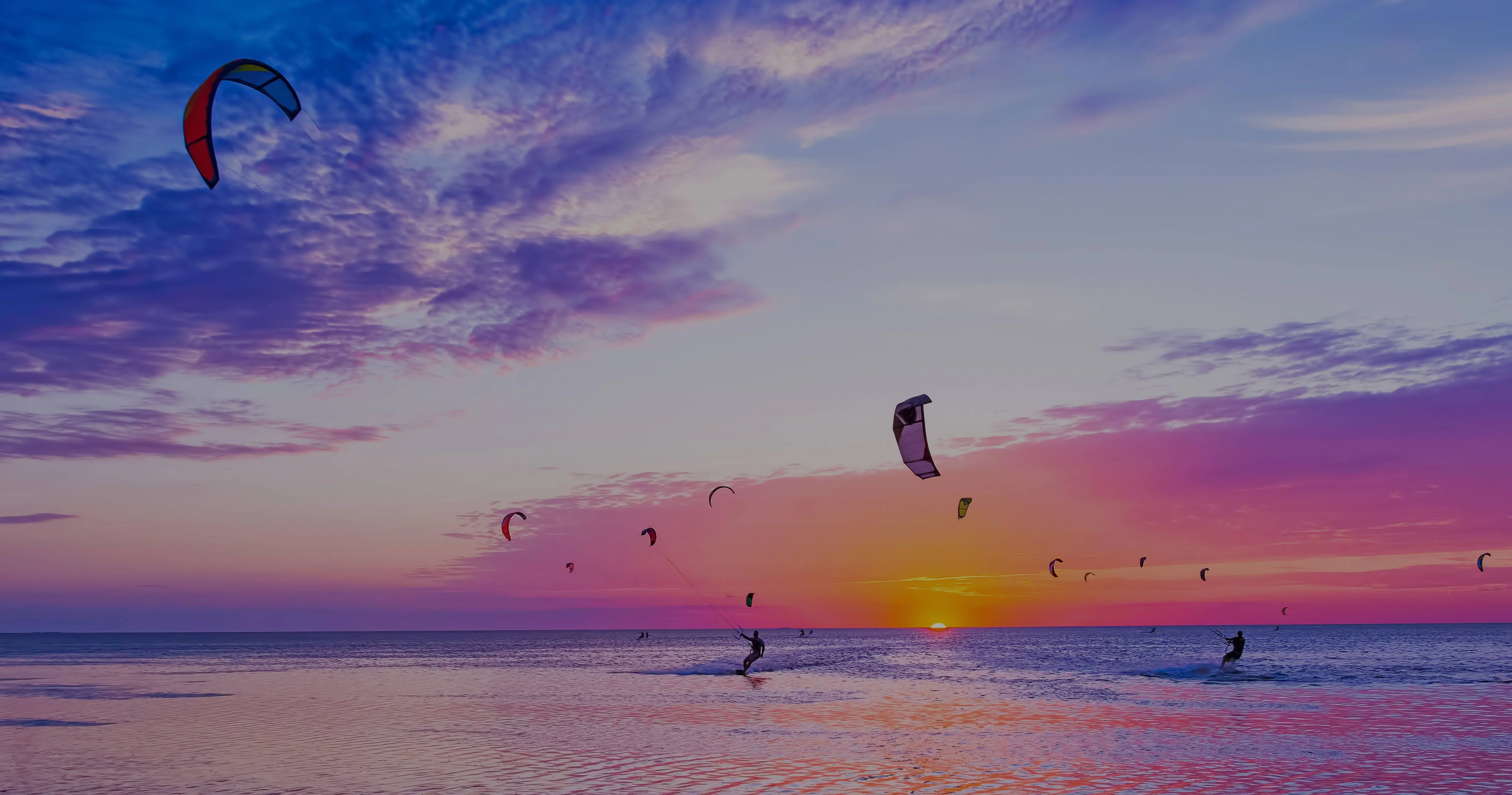 beautiful ocean sunset with kit surfers enjoying the ride