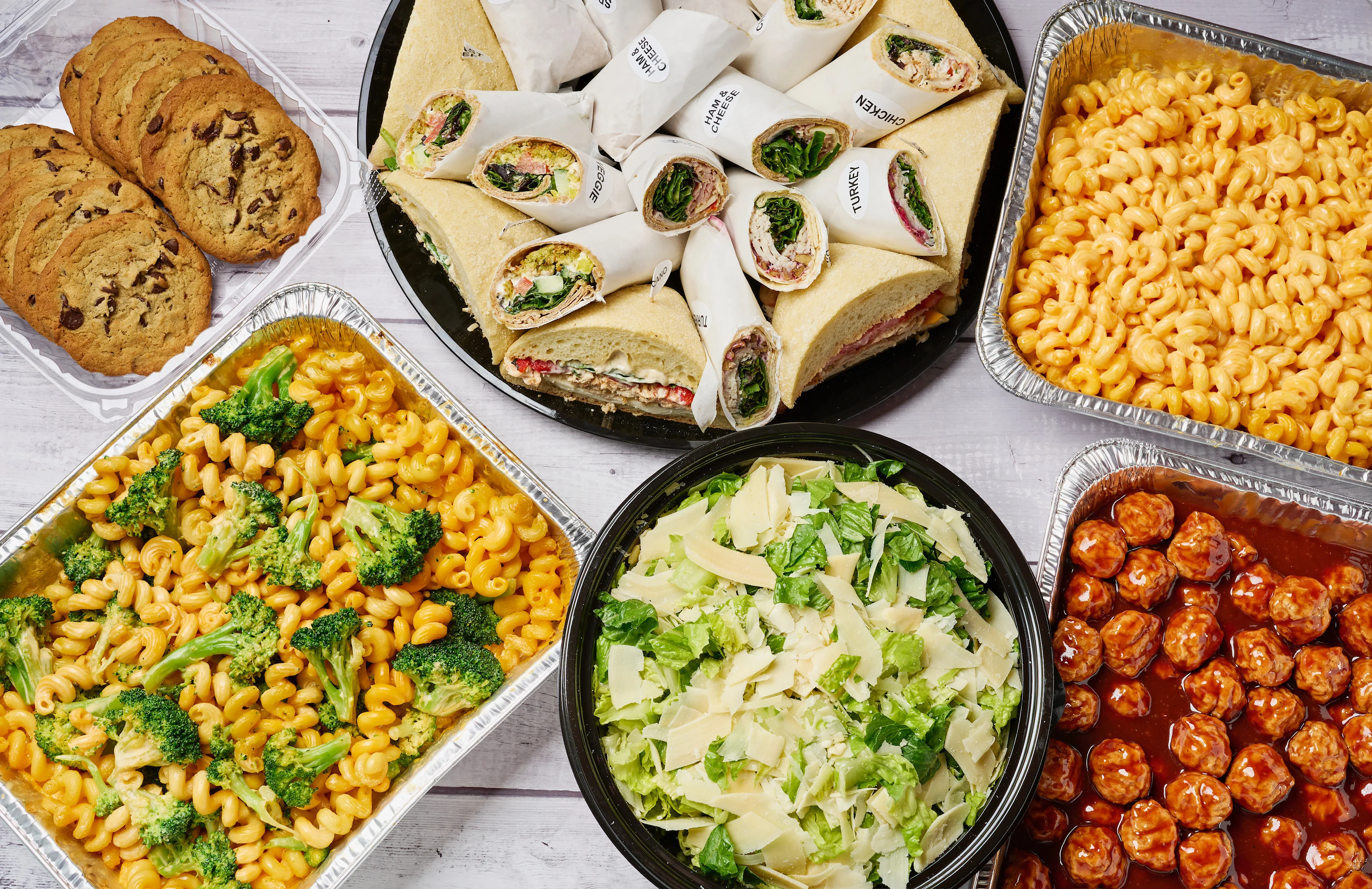 Assorted catering platter with wraps, pasta, salad, and cookies