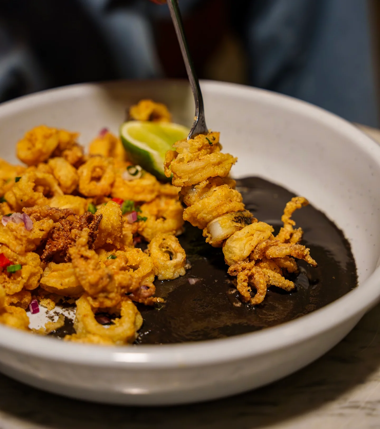 Crispy calamari served with black sauce and lime wedge