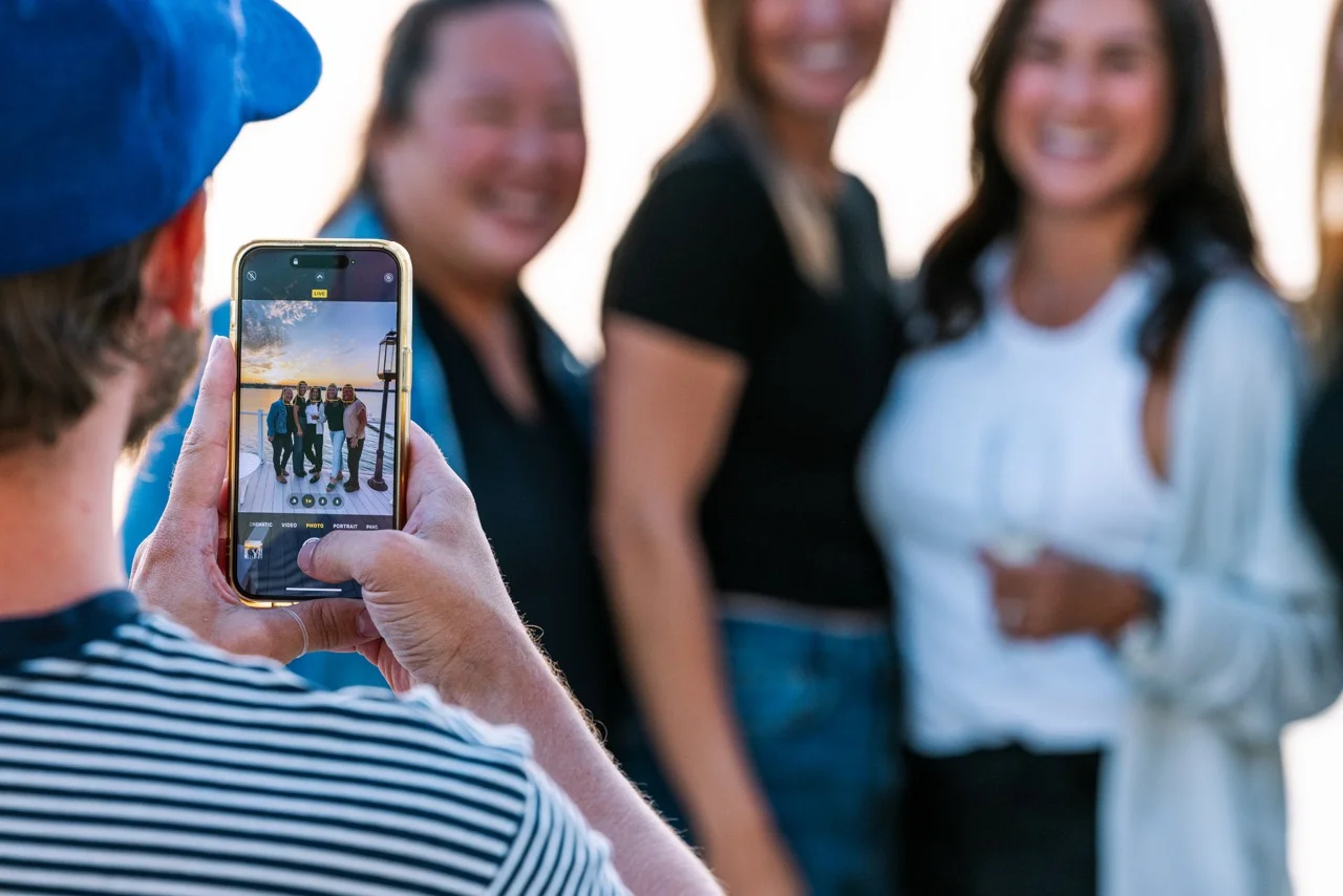 Group of friends posing for a photo at sunset by the water