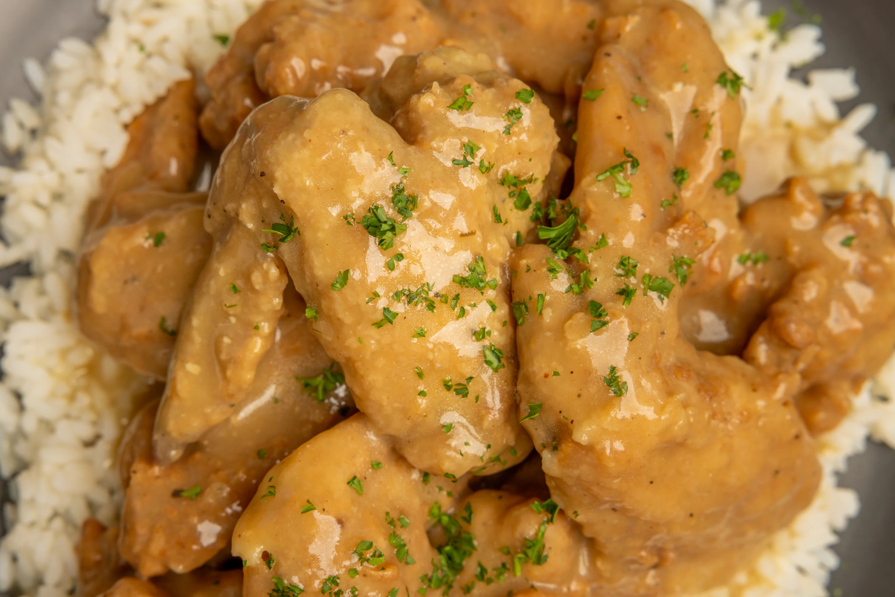 Six fried chicken wings smothered in sauce on a plate.