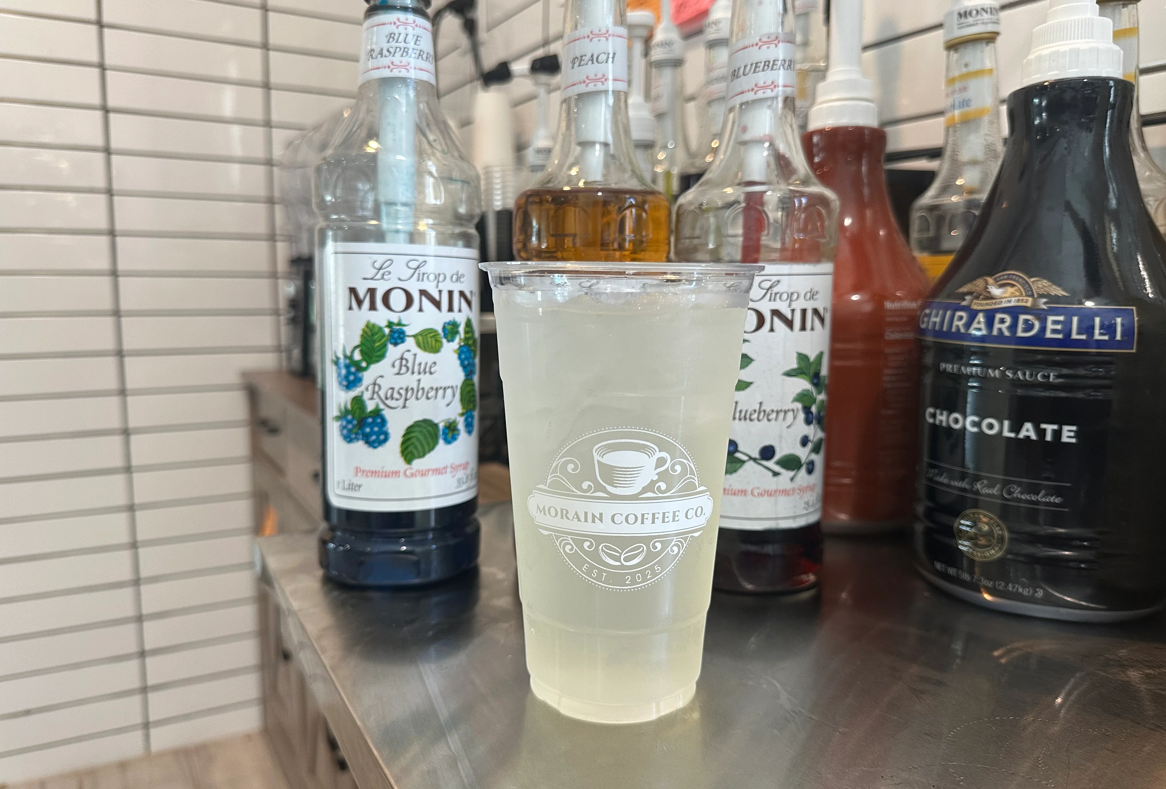 Medium Sized Lemonade in front of Flavored Syrups