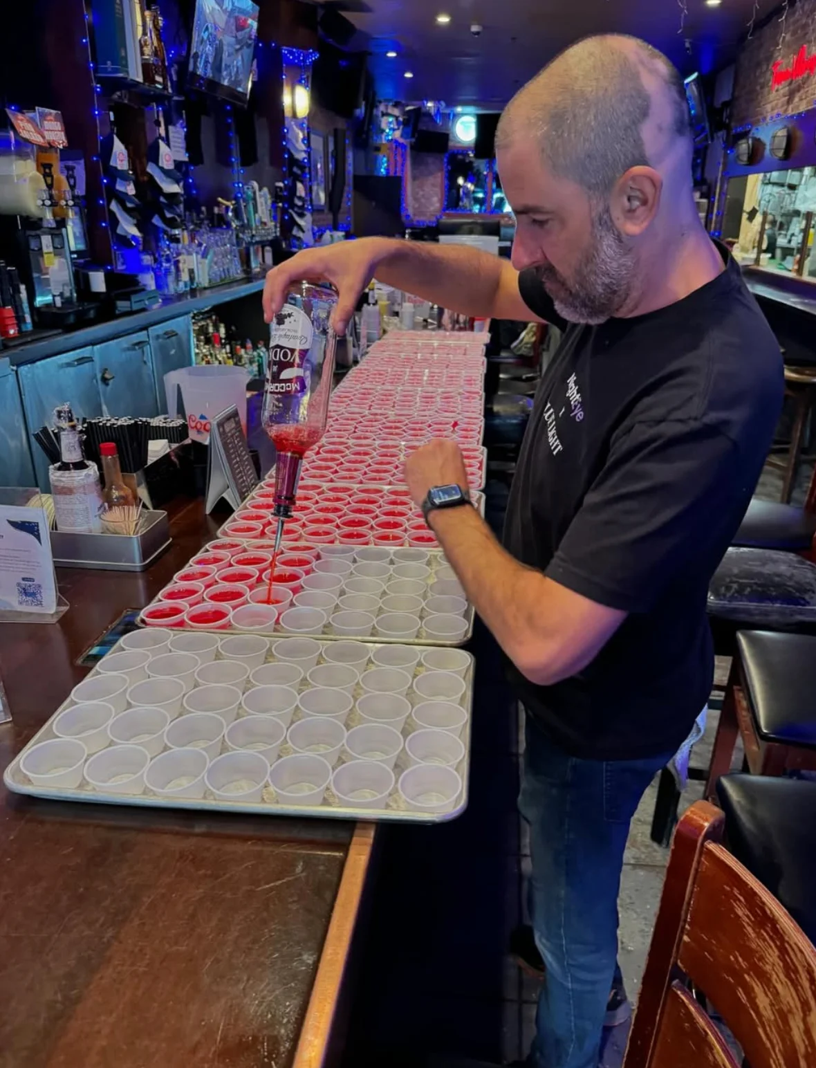 Bartender preparing colorful shots at a lively bar