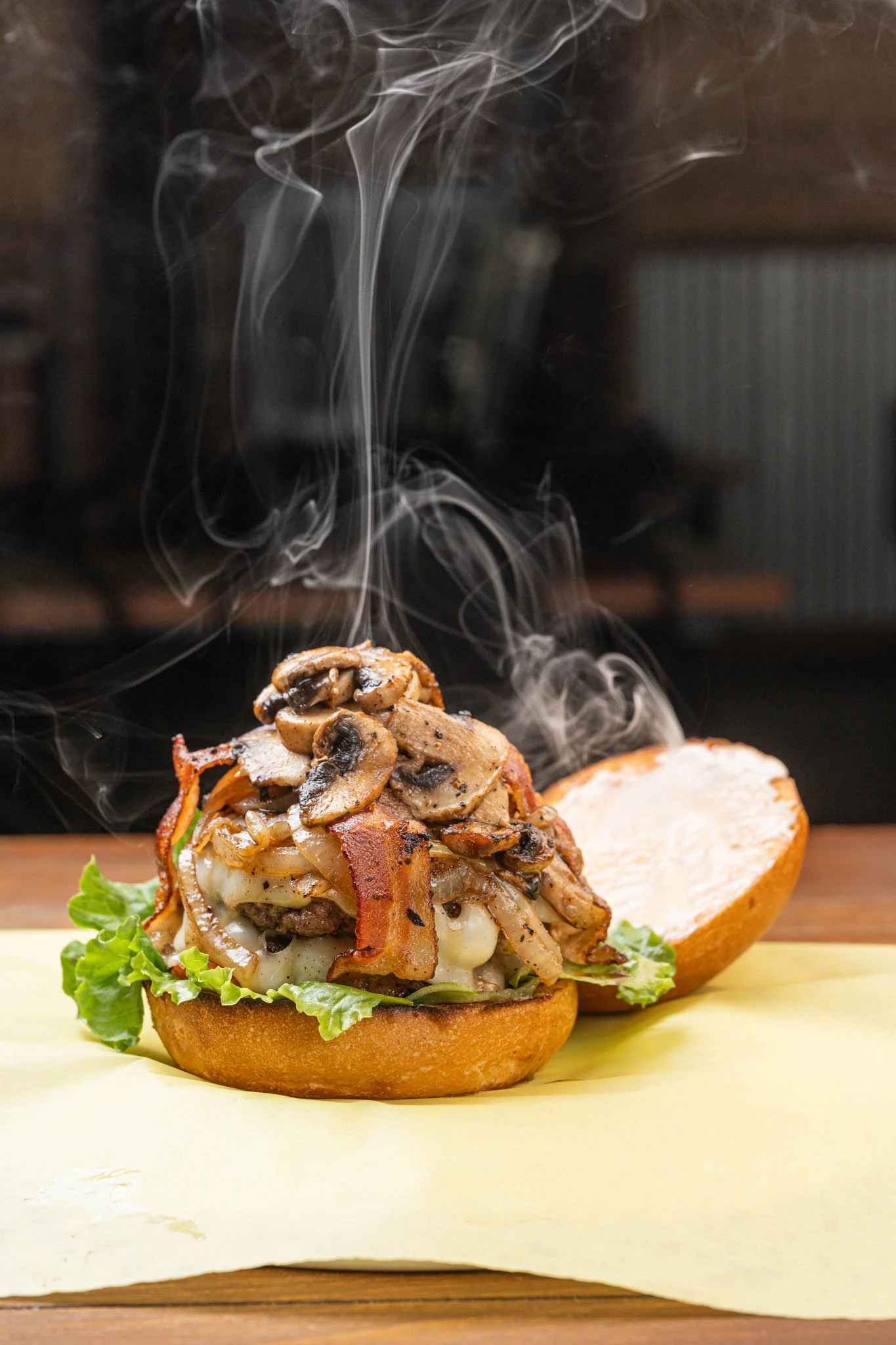Juicy mushroom bacon burger with fresh toppings on a wooden table.