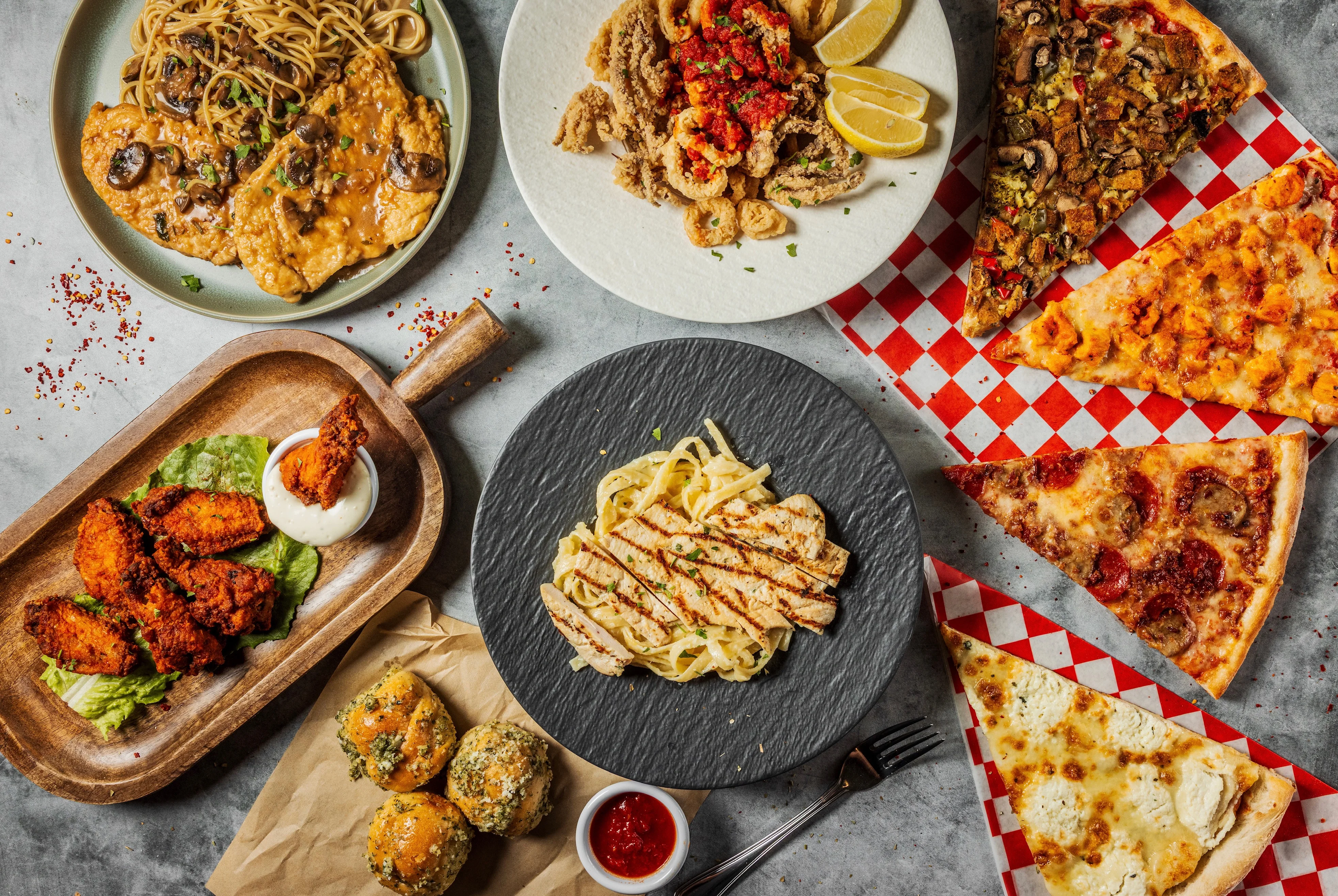 Assorted Italian favorites including pizza slices, chicken wings, pasta dishes, and garlic knots from Tommy’s Pizza in South Richmond Hill, Queens NY