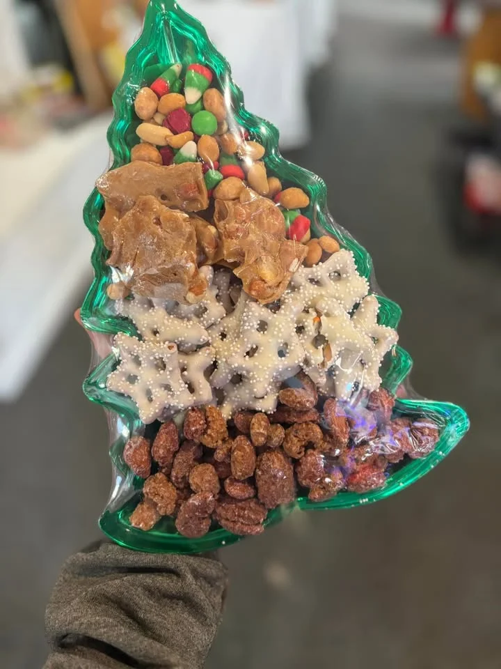 A festive Christmas tree-shaped tray filled with assorted snacks, including nuts, chocolate, and pretzels.