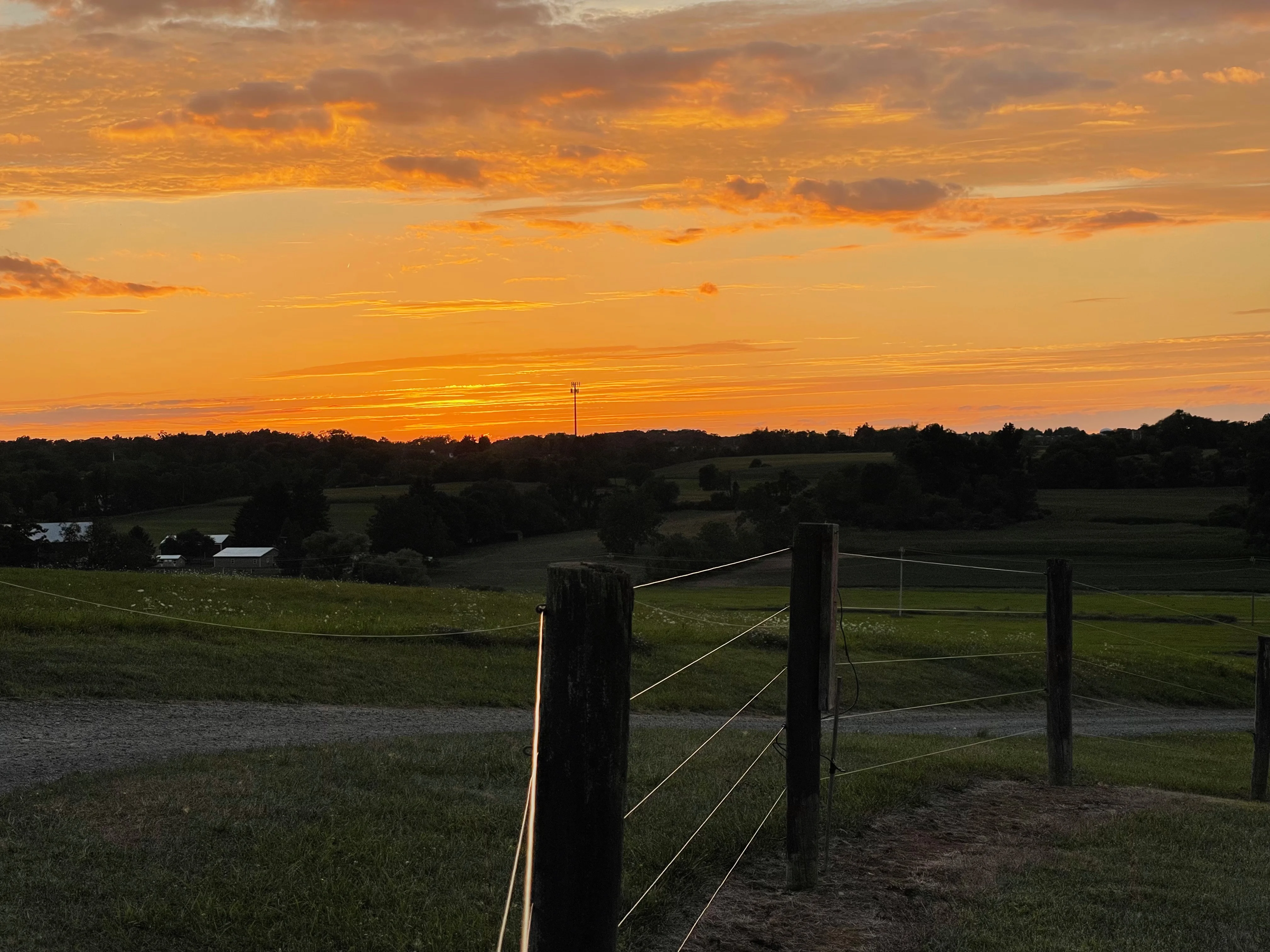 Scenic sunset over rolling hills and a wooden fence