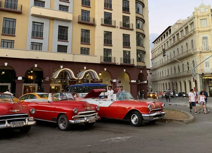Classic vintage cars parked near a historic hotel