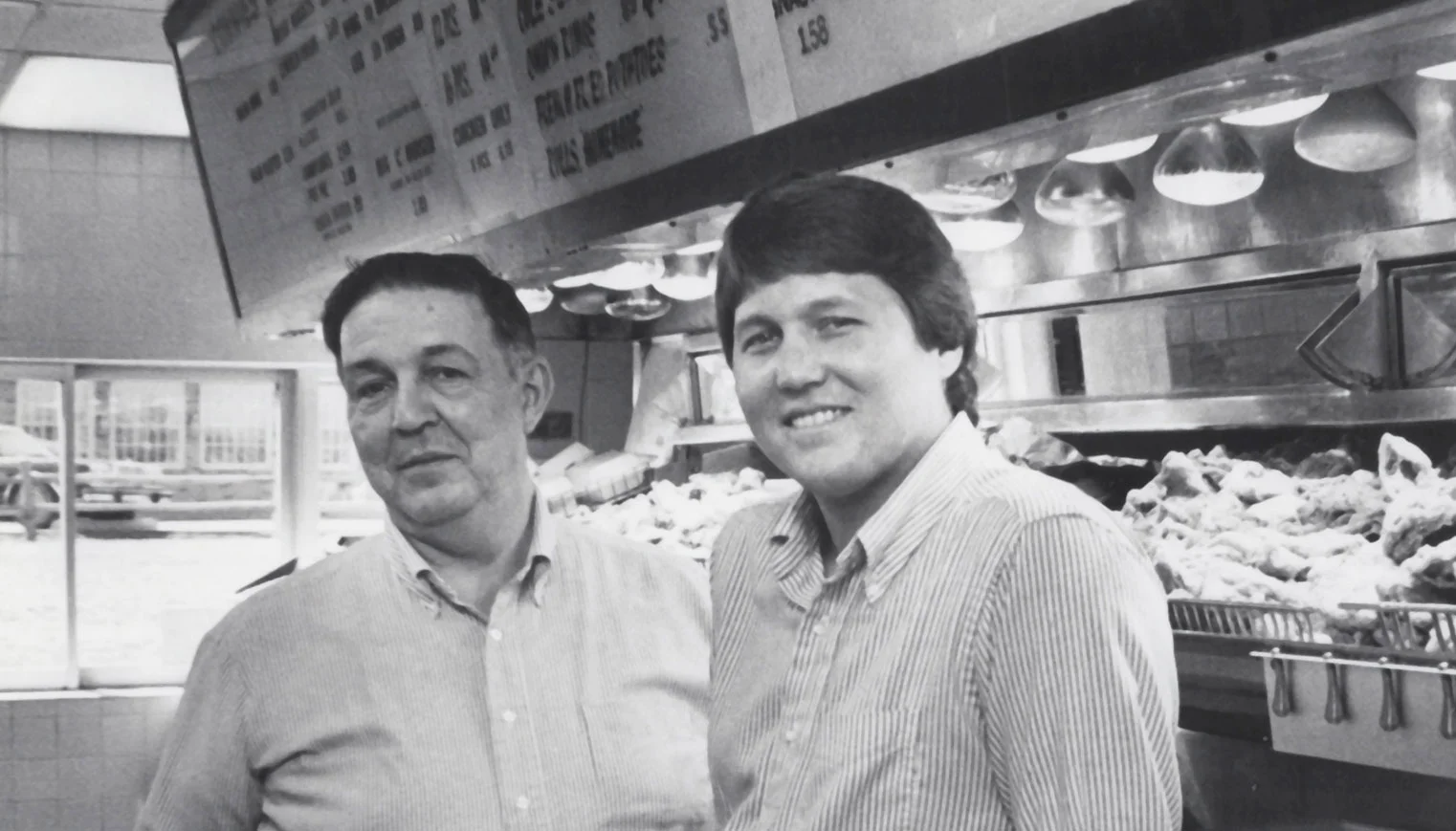 Two restaurateurs in a classic diner setting with fried chicken display