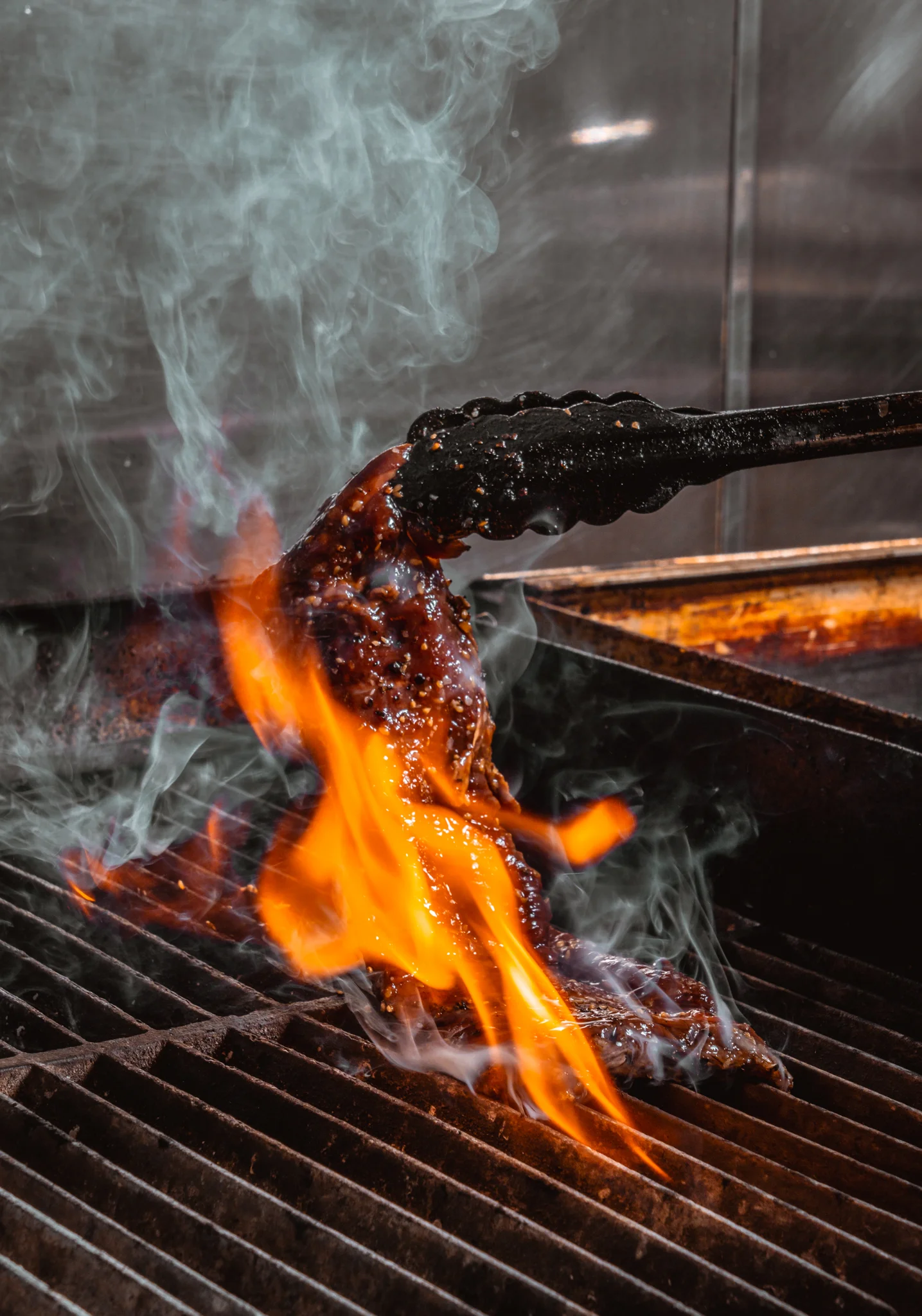 Grilled steak with flames on a grill, showcasing a delicious meal.