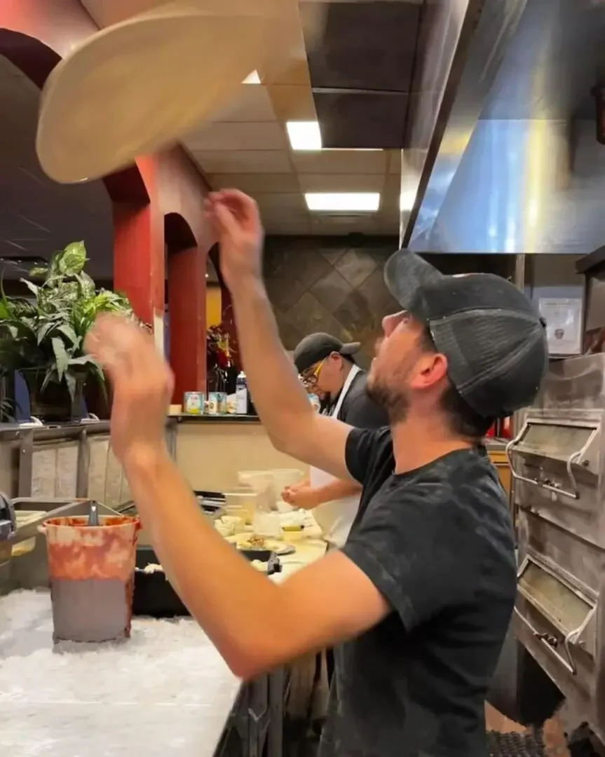 Pizza chef tossing dough in a lively kitchen