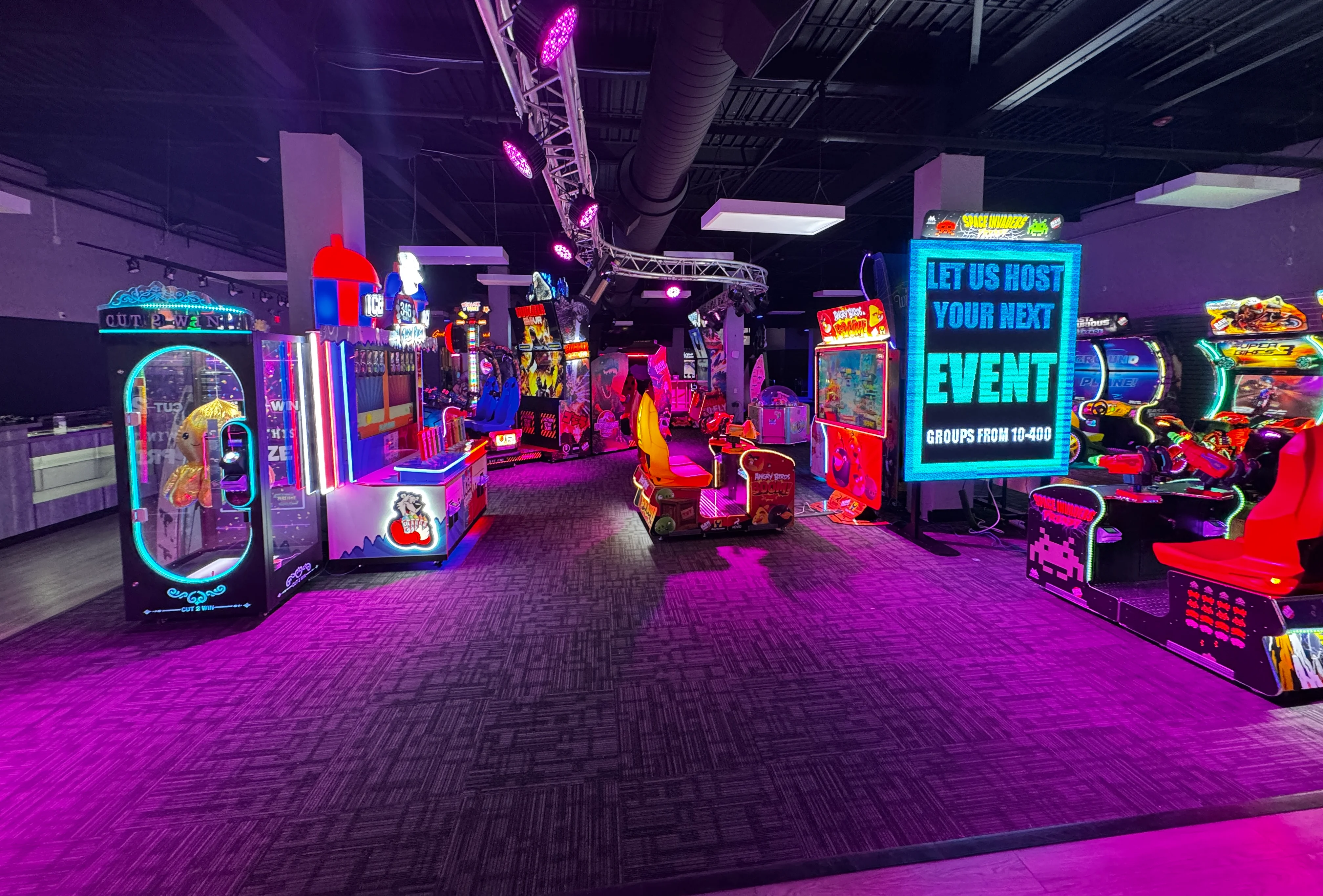 Vibrant arcade with various games and event hosting sign