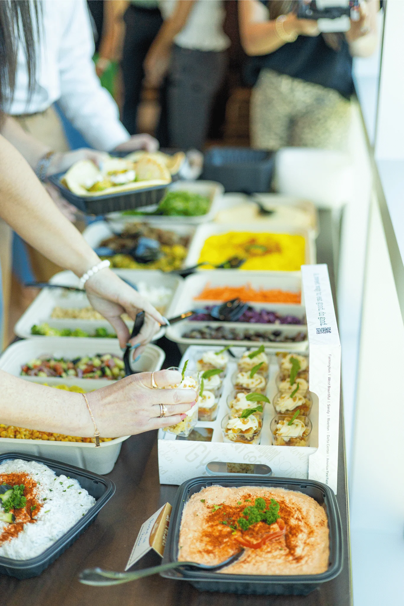 Server spooning rice and sauce from a Santorini's Greek Grill catering buffet, featuring signature dishes like the Braised Beef and Spicy Honey Chicken buffets.