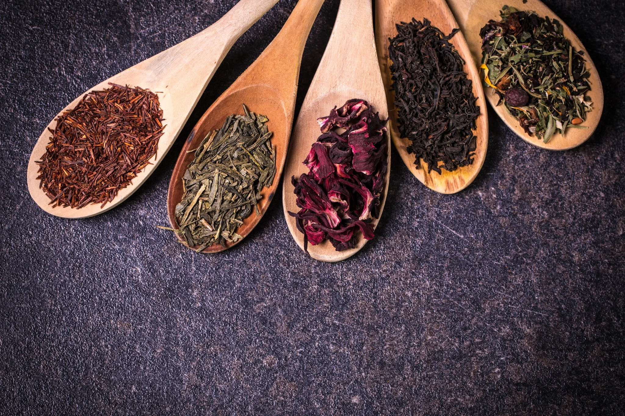 Variety of loose teas in wooden spoons
