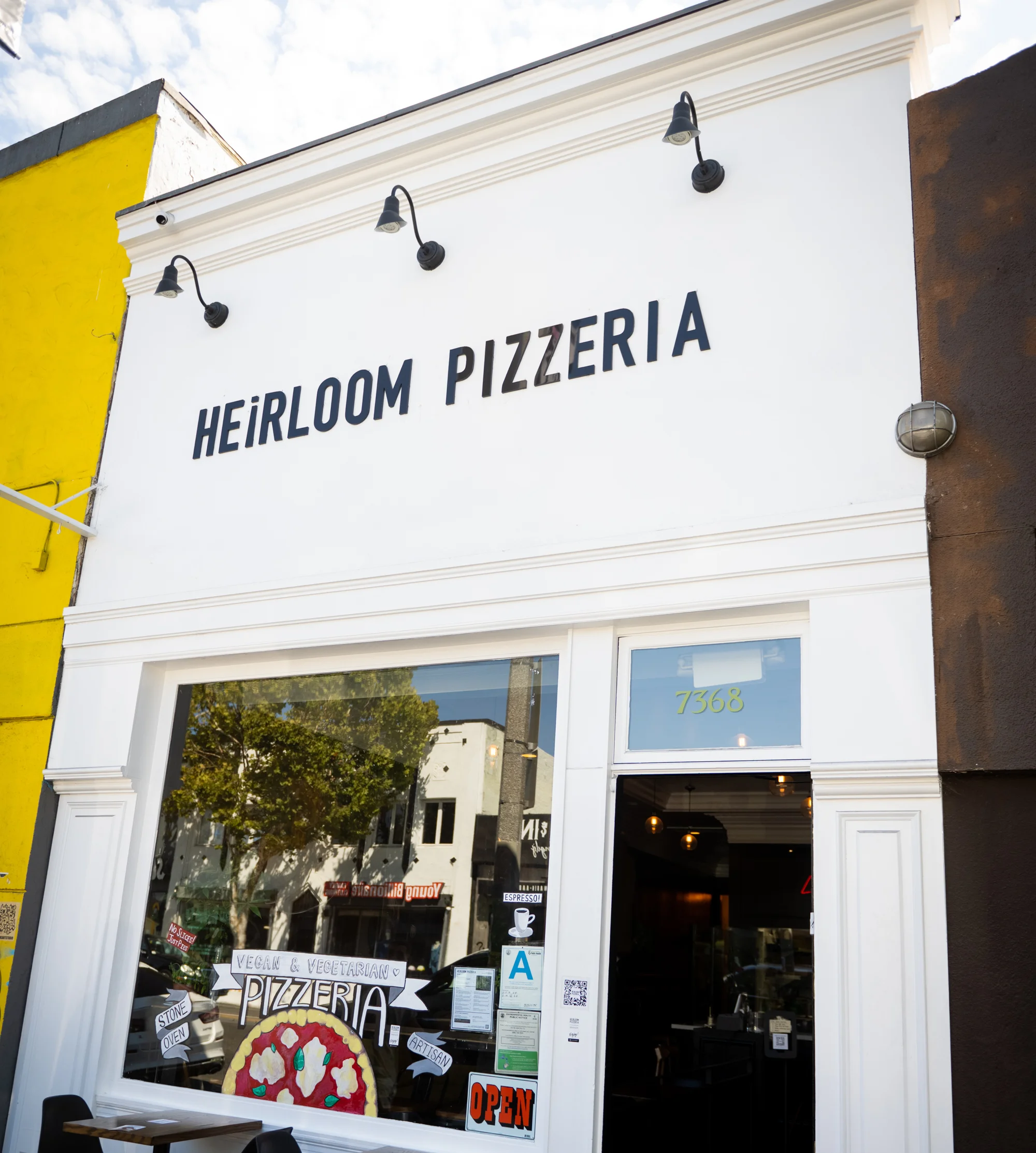 Exterior of Heirloom Pizzeria with open sign and outdoor seating