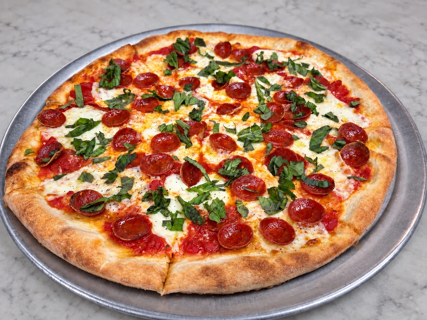 Pasquale’s crispy-cup pepperoni pizza with fresh mozzarella and basil on a metal pizza tray