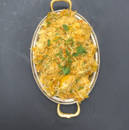 Vegetable biryani or chicken biryani in an oval metal serving dish.