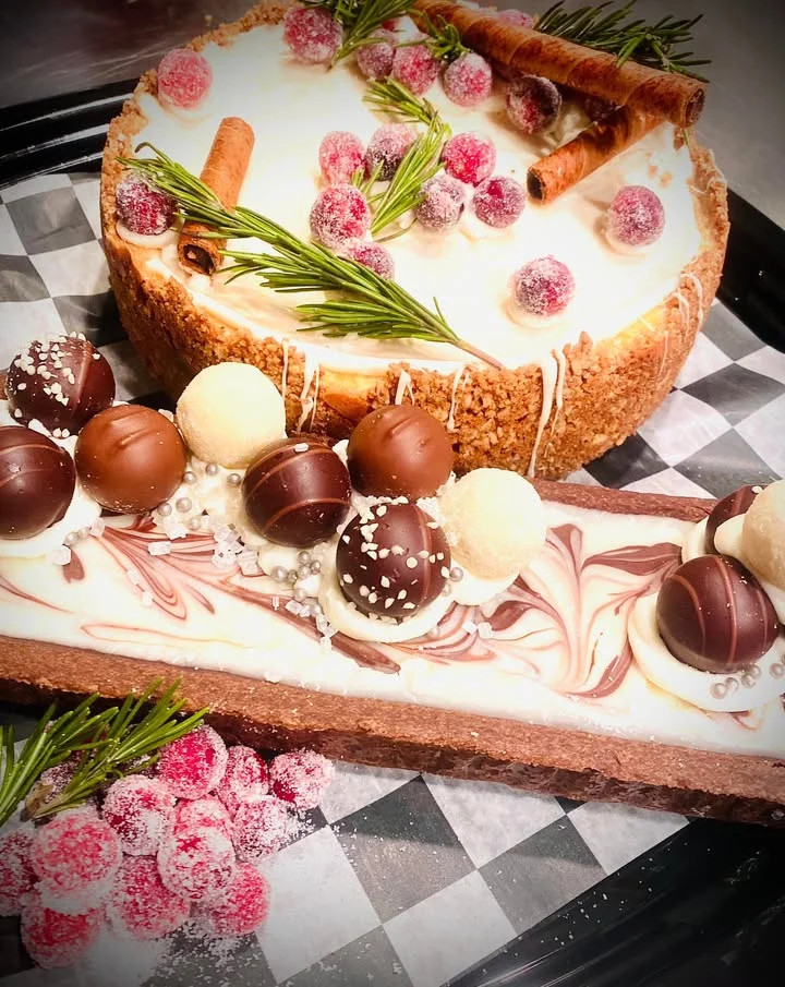 An elegant dessert display featuring a cheesecake topped with fresh fruits and decorated chocolate truffles.