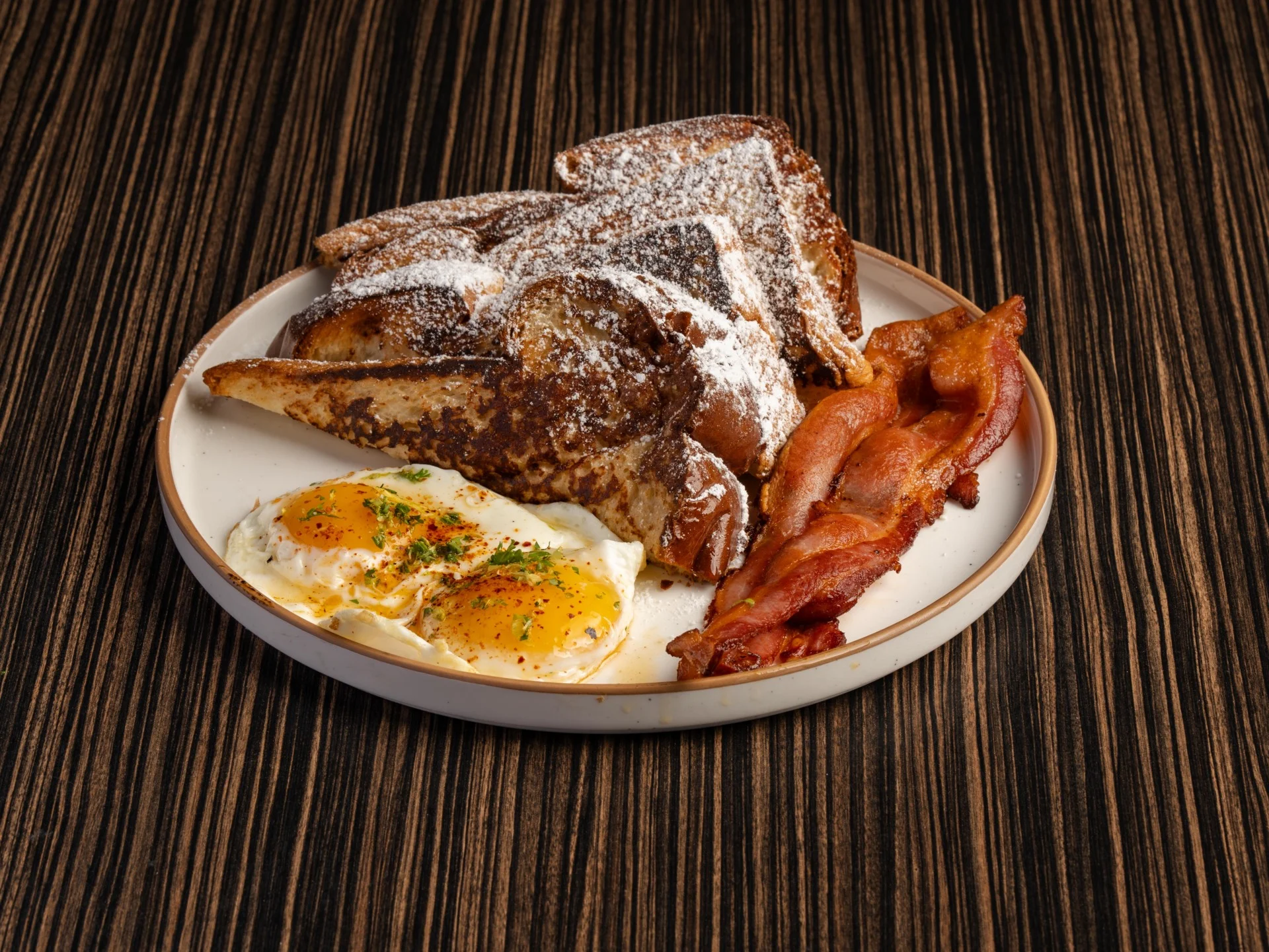 French toast with eggs and bacon on a plate