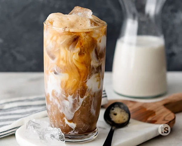 Iced coffee with milk swirls in a tall glass