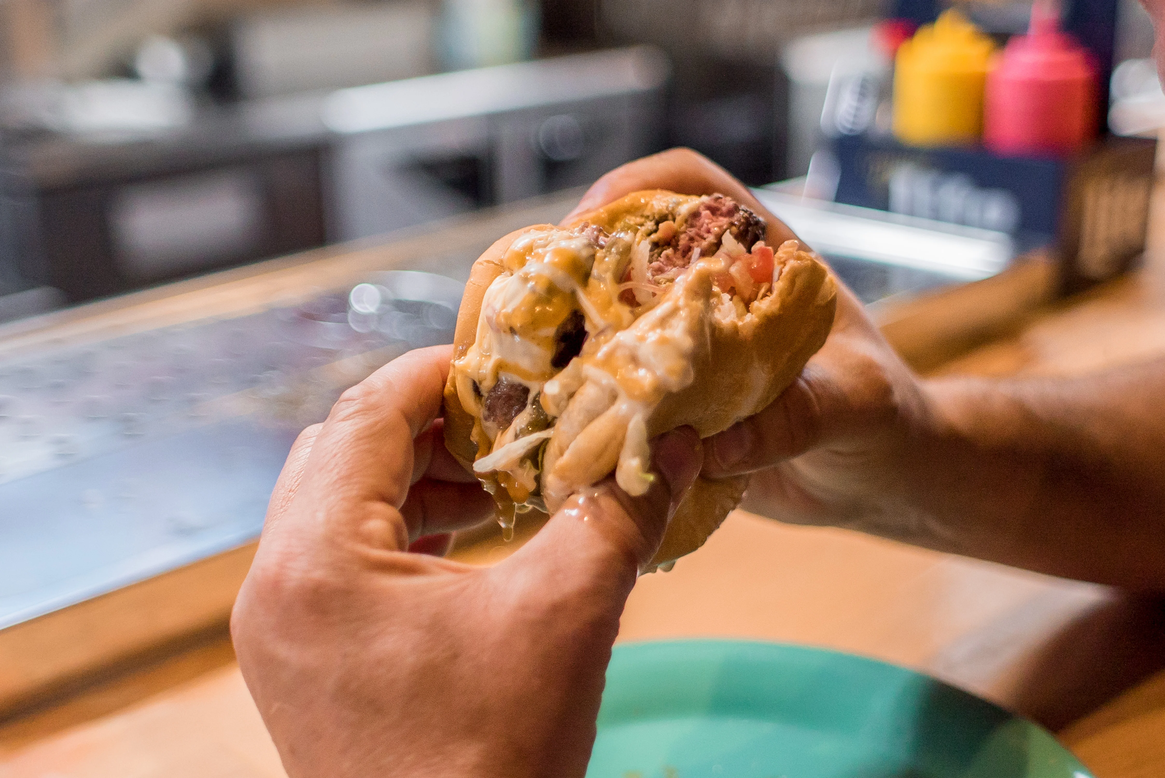 Juicy cheeseburger with toppings in hand