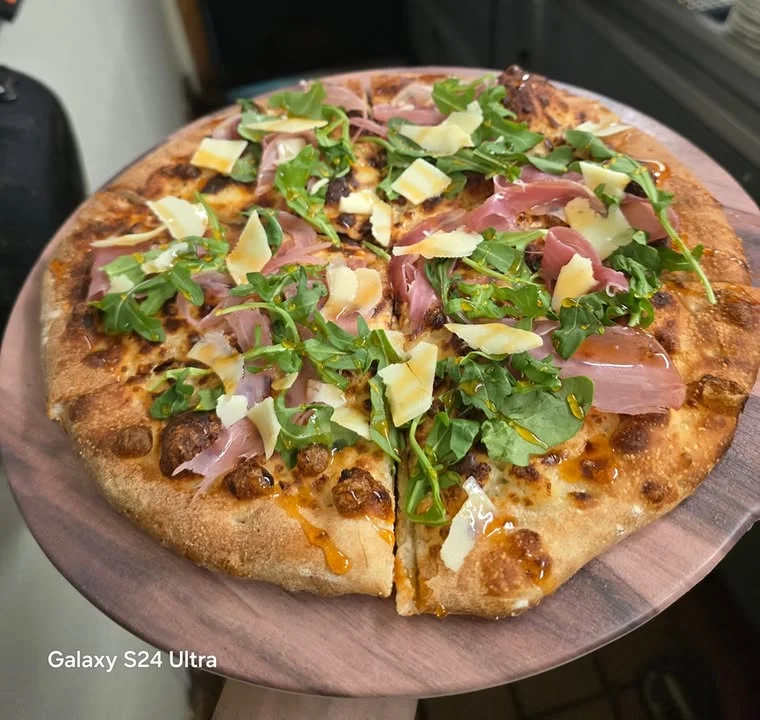 Gourmet pizza topped with prosciutto and arugula