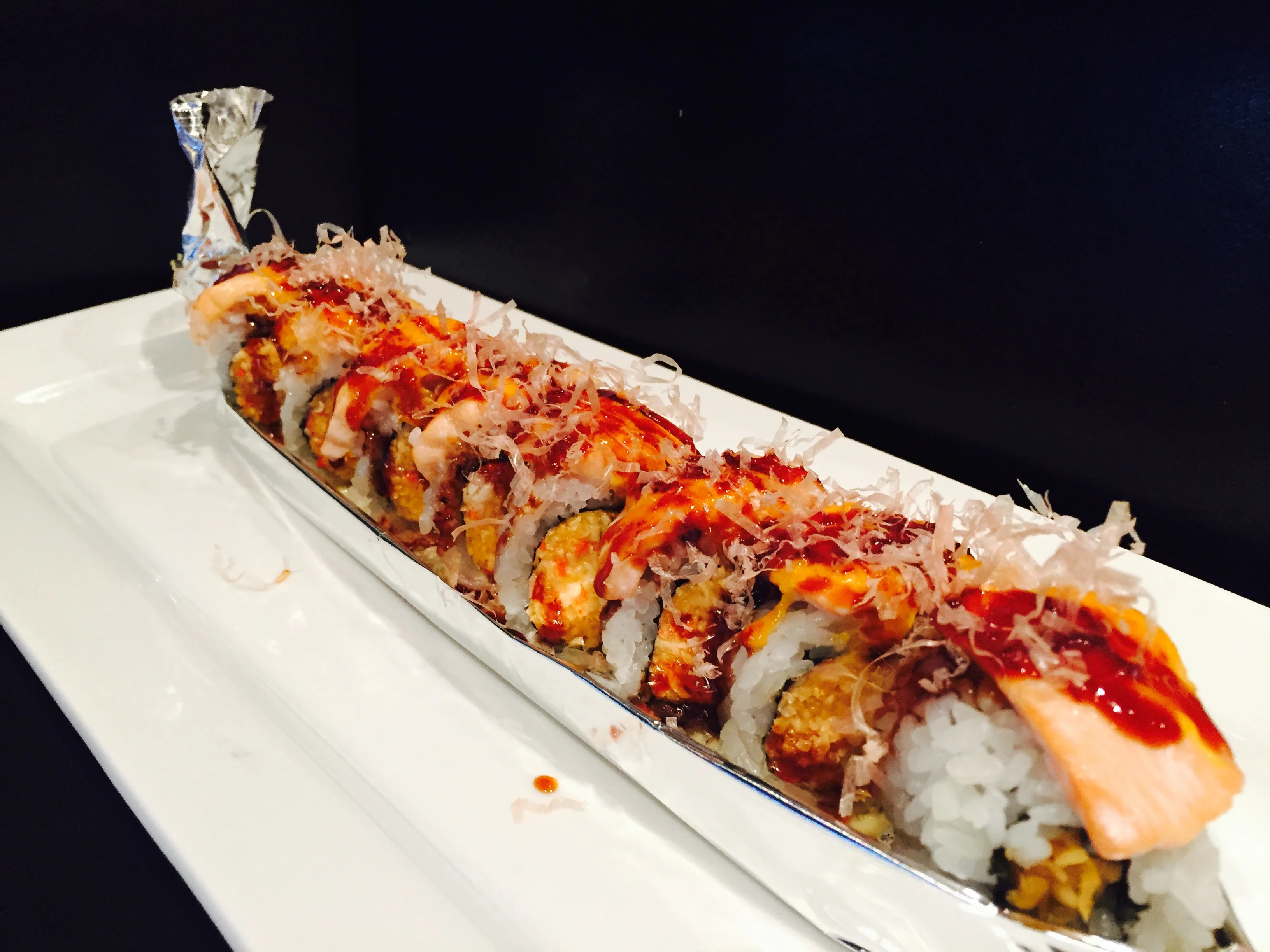 Baked salmon roll with avocado and garnishes on a plate
